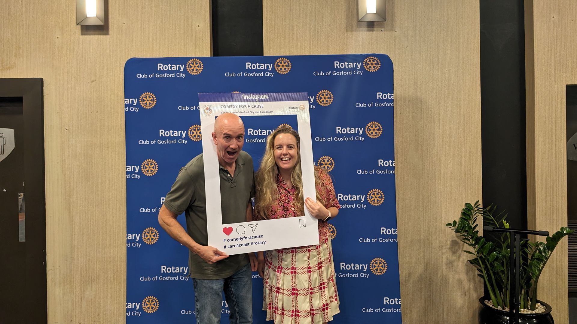 A man and a woman are posing for a picture with a picture frame.
