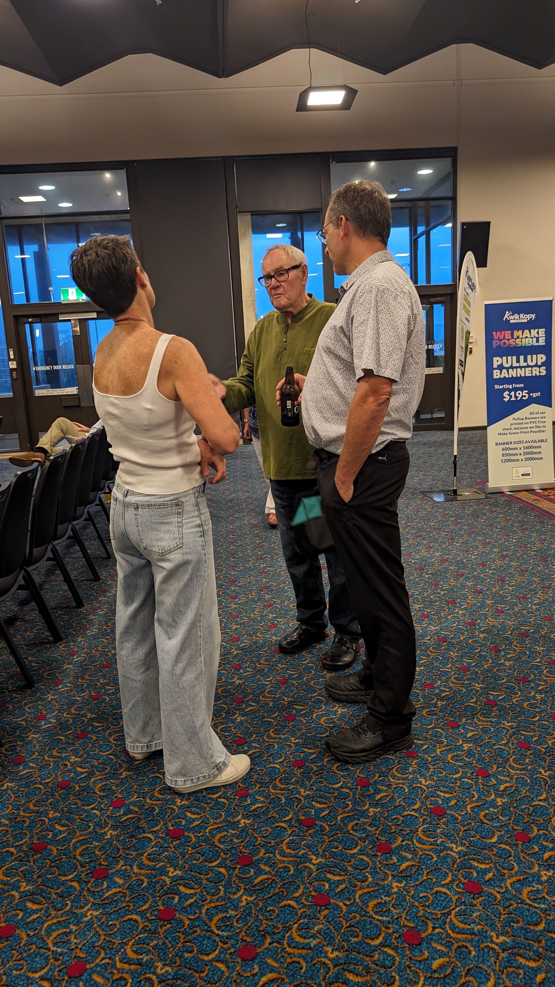 A group of people are standing in a room talking to each other.