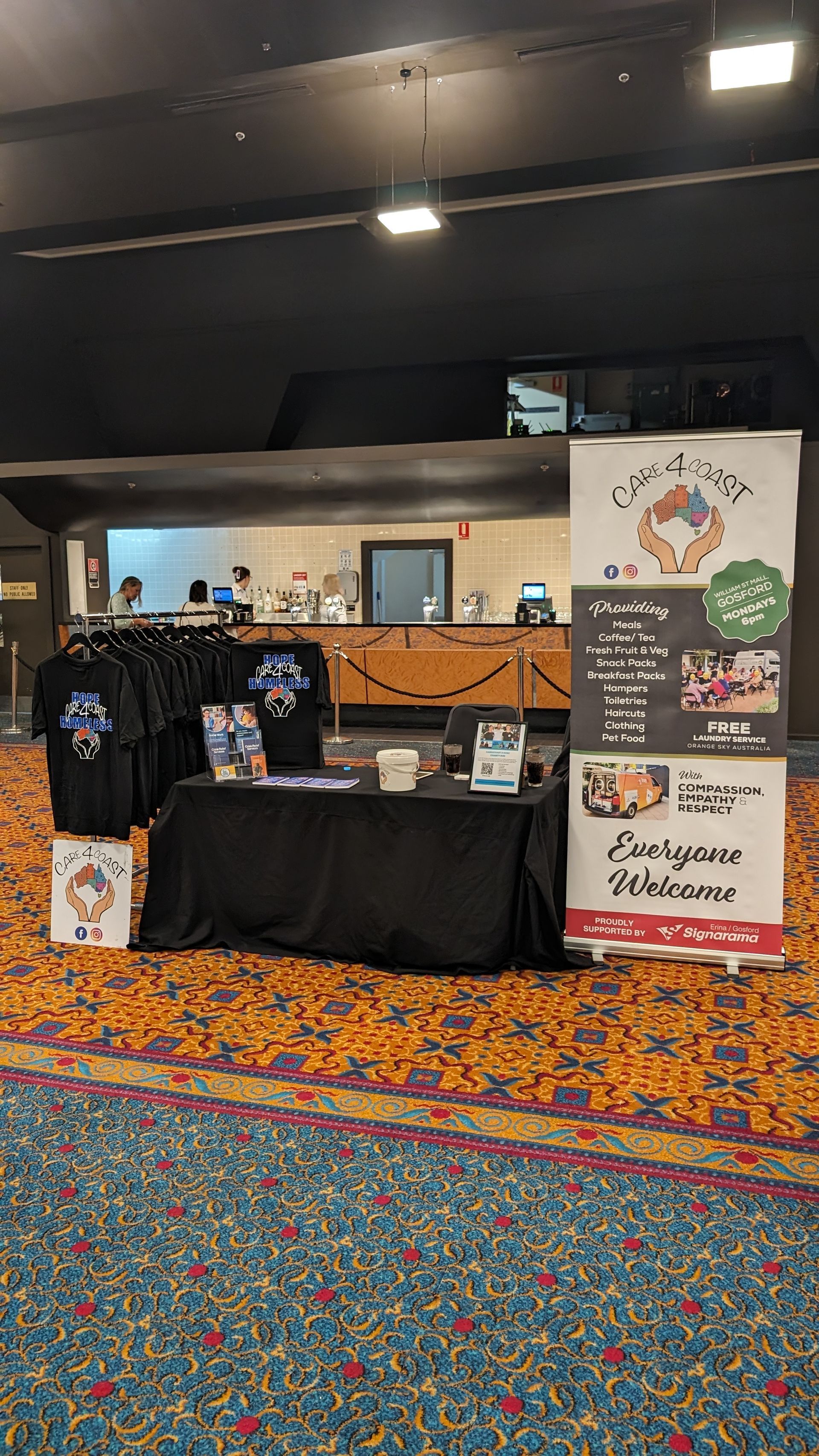 A table with a sign on it in a room with a carpet.