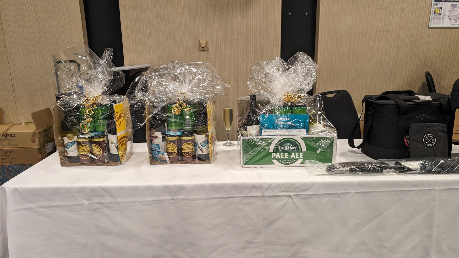 A table with three gift baskets wrapped in plastic on it.