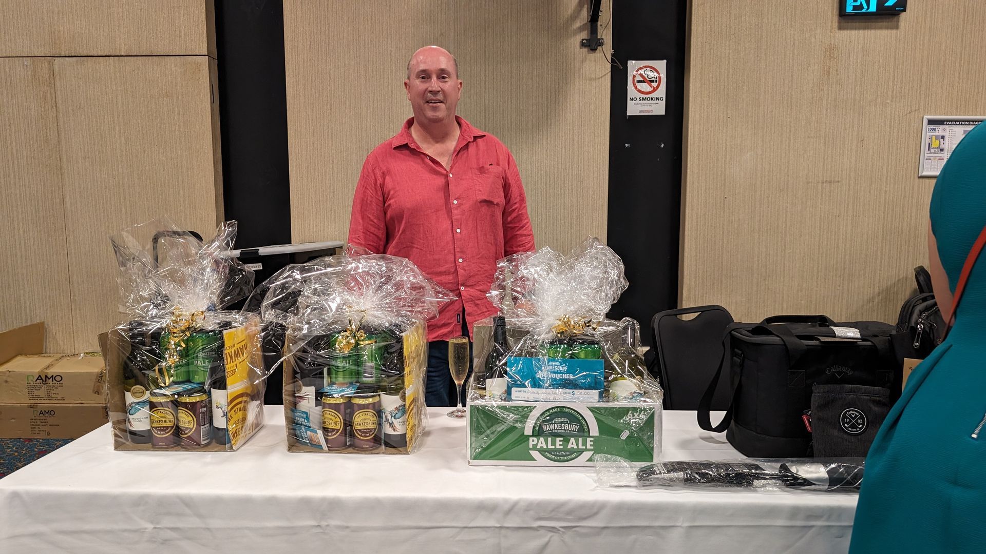 A man in a red shirt is standing in front of a table with baskets of food on it.
