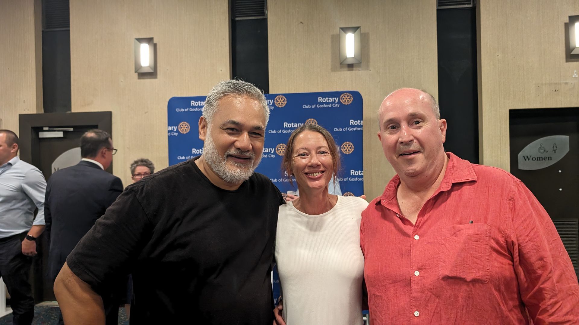 Three people are posing for a picture together in a room.