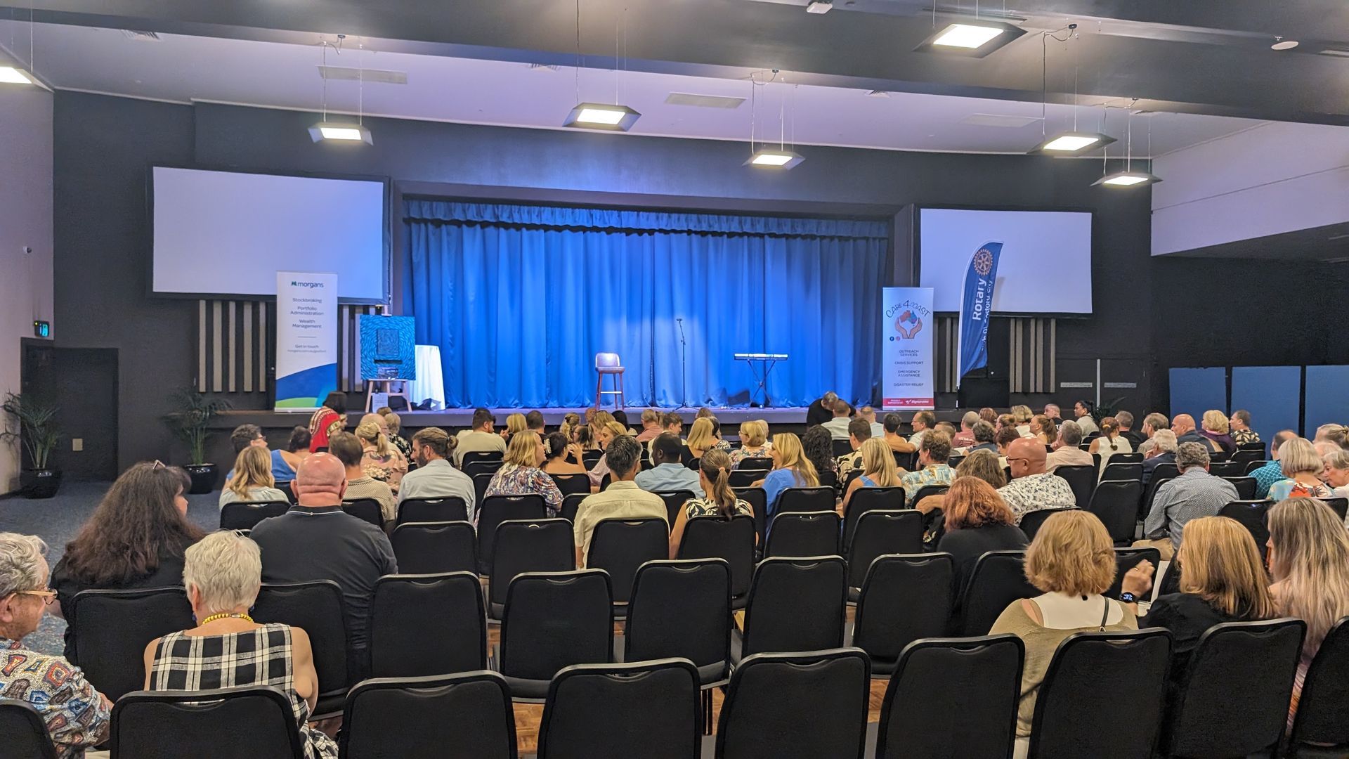 A large group of people are sitting in an auditorium watching a presentation.