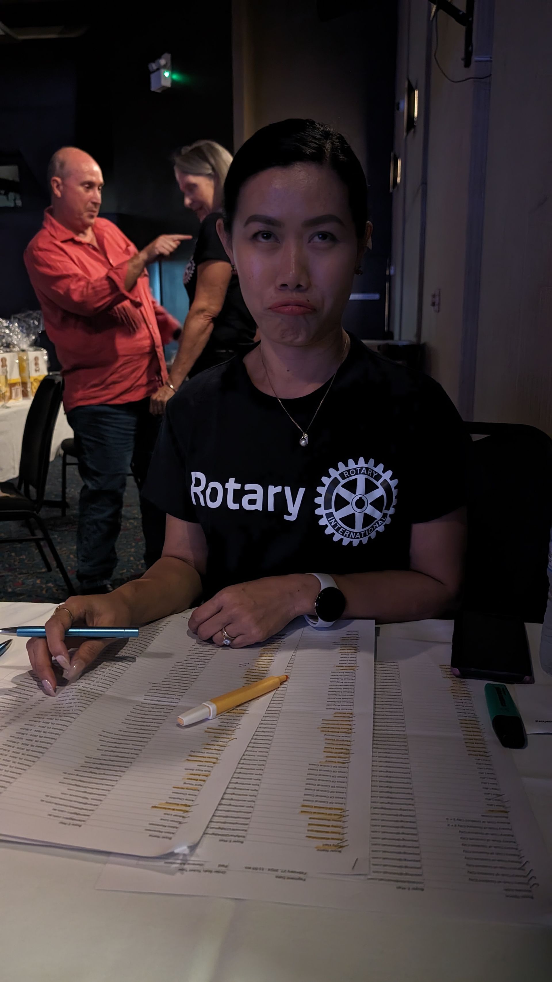 A woman is sitting at a table with a rotary shirt on.
