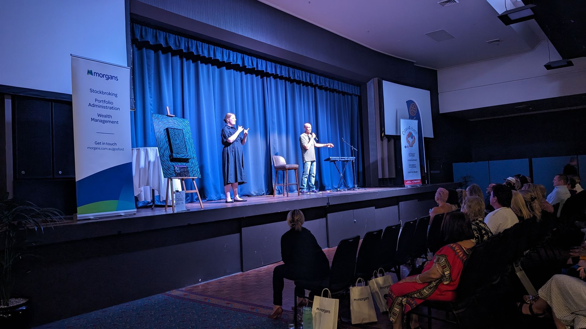 A group of people are sitting in an auditorium watching a performance on a stage.