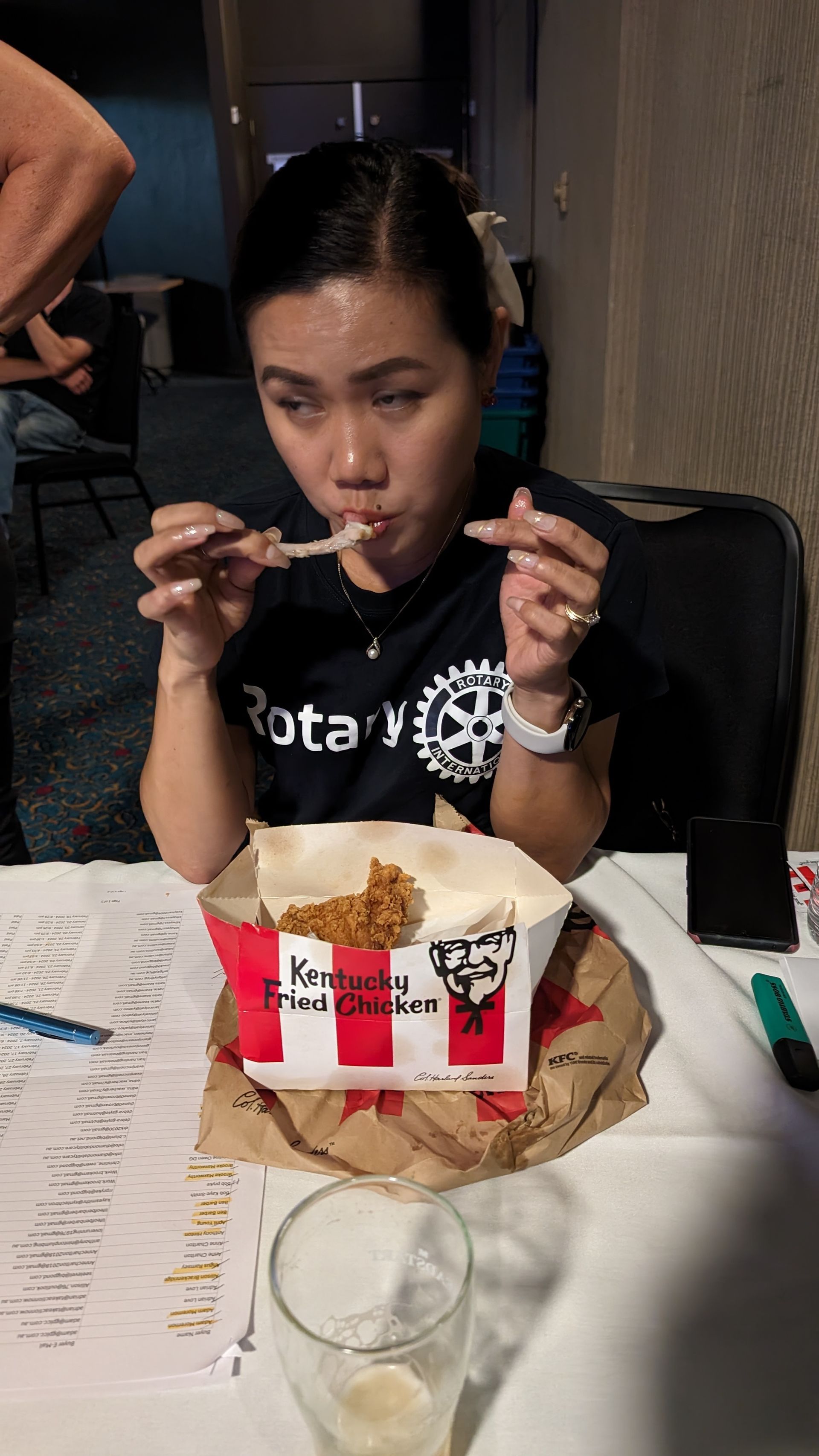A woman is sitting at a table eating kfc fried chicken.