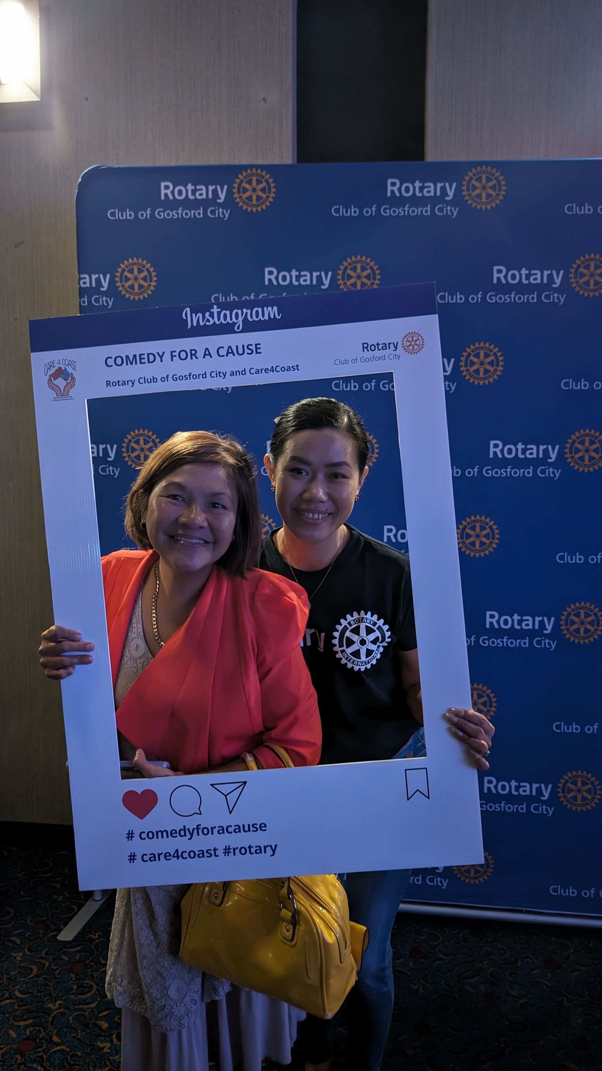 Two women are posing for a picture with a picture frame.