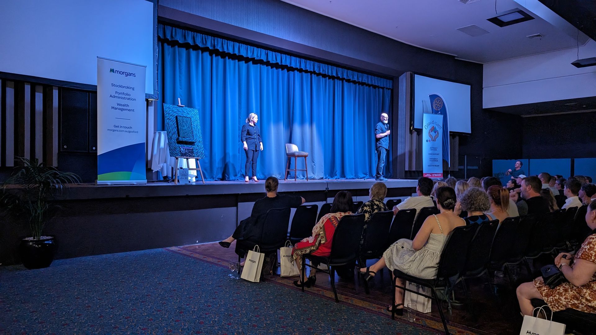 A group of people are sitting in chairs in front of a stage.