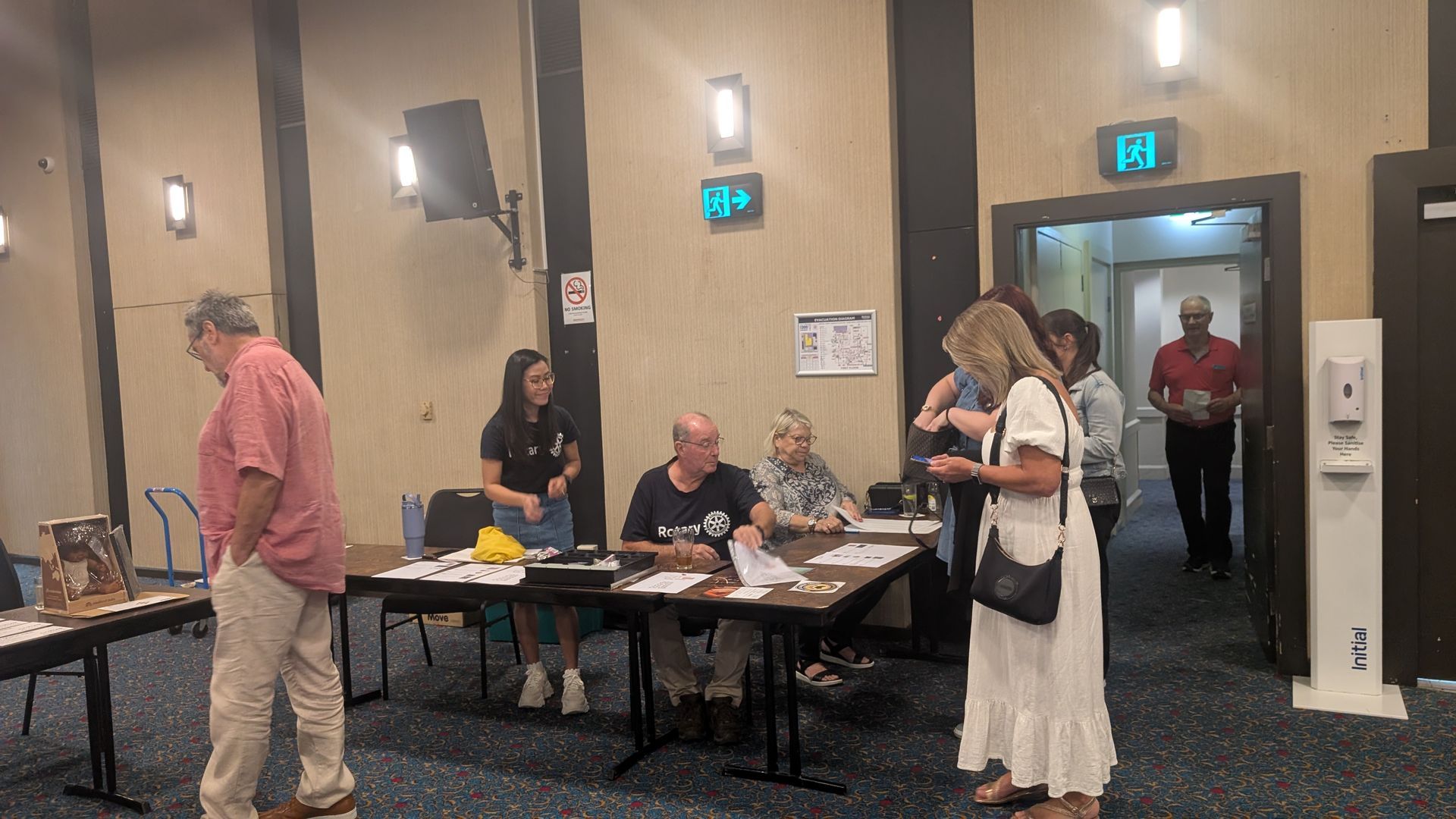 A group of people are standing around tables in a room.