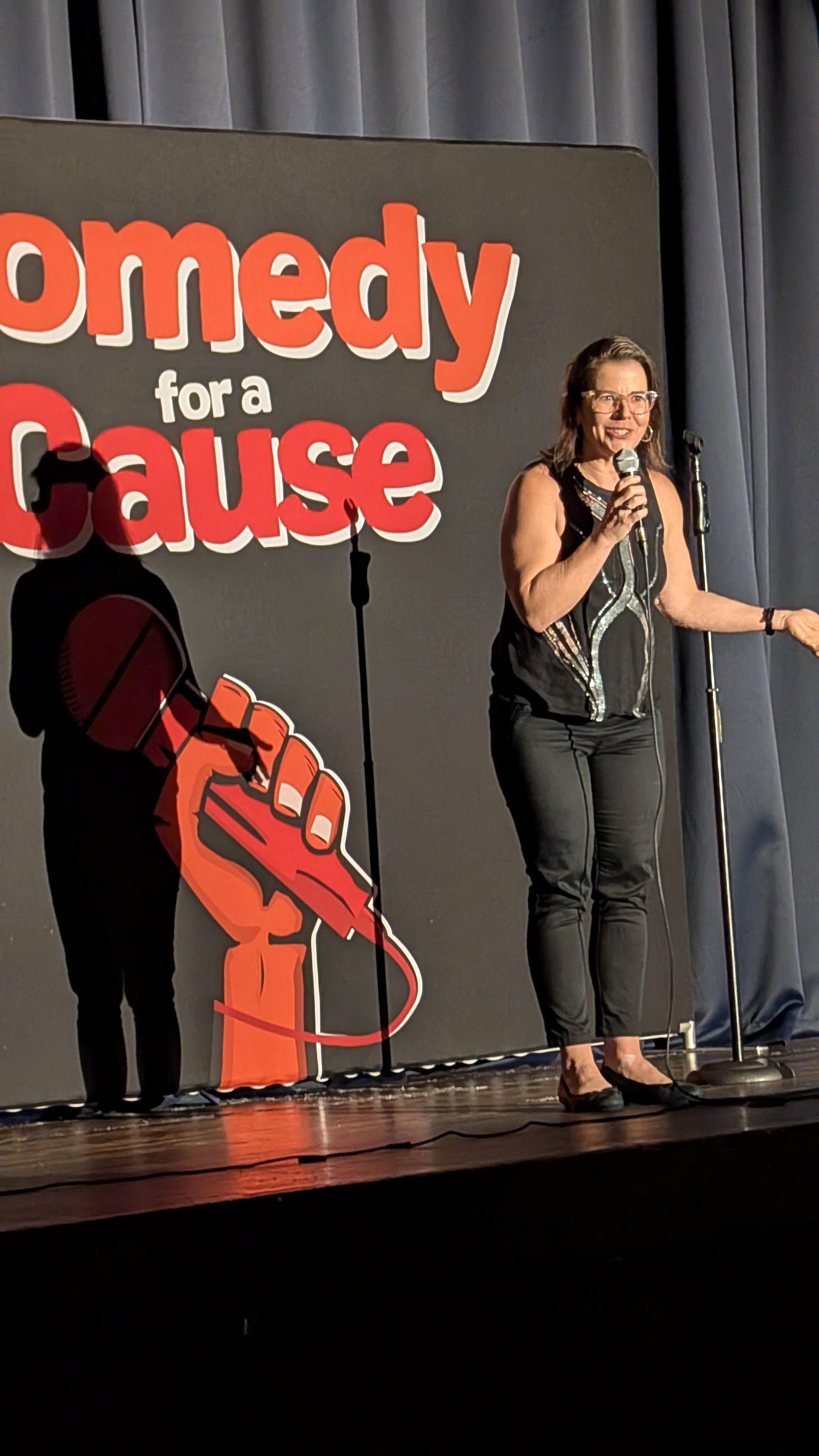 A woman is standing in front of a sign that says comedy for a cause