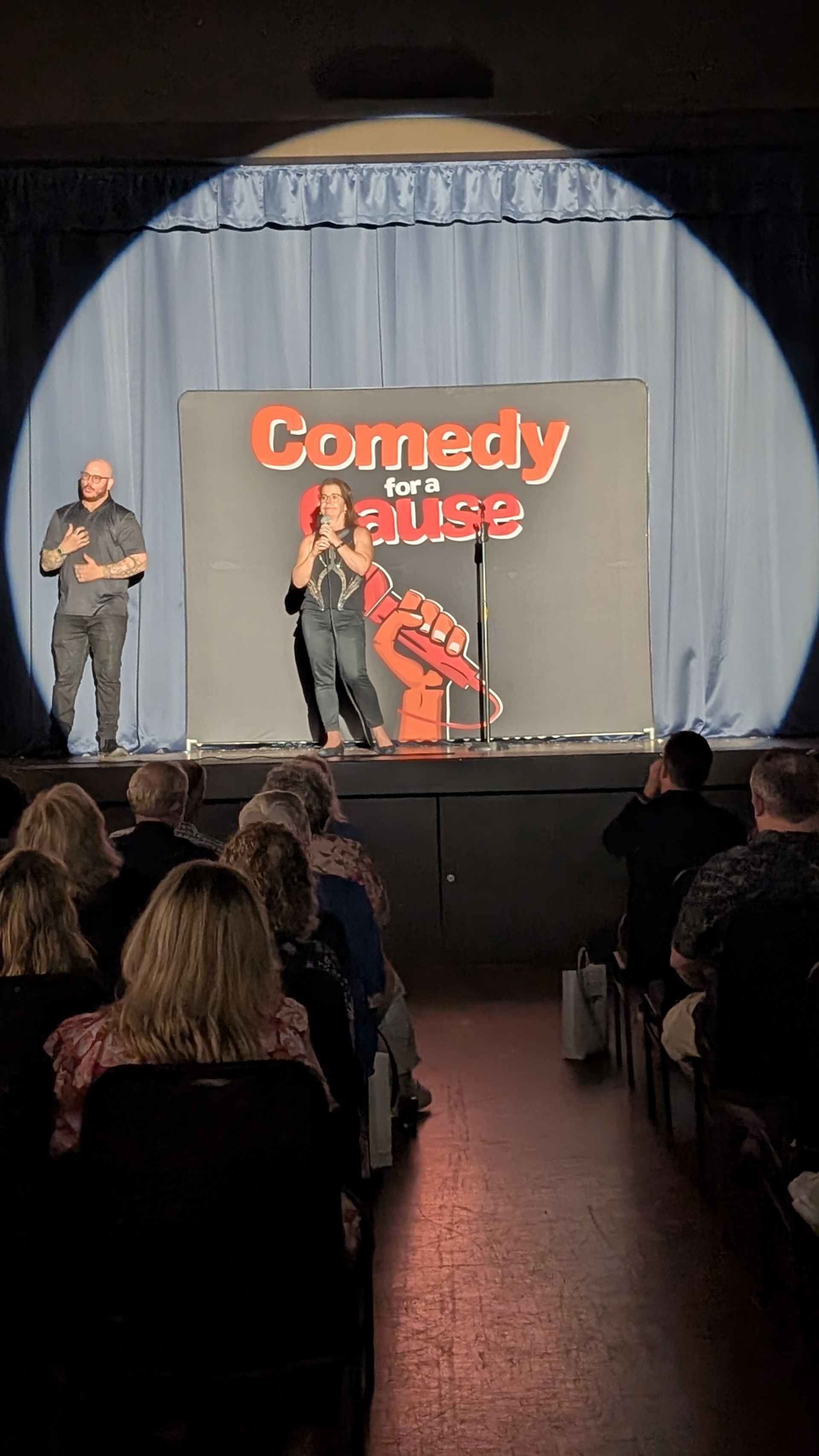 A man and a woman are standing on a stage in front of a crowd.