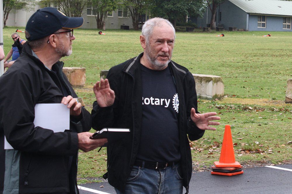 A man wearing a rotary shirt is talking to another man