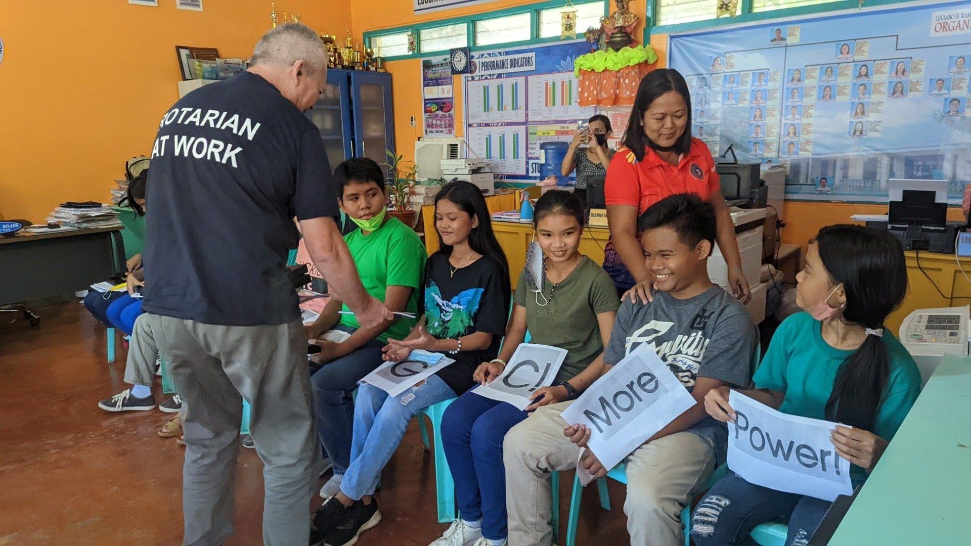 A man is talking to a group of children in a classroom.