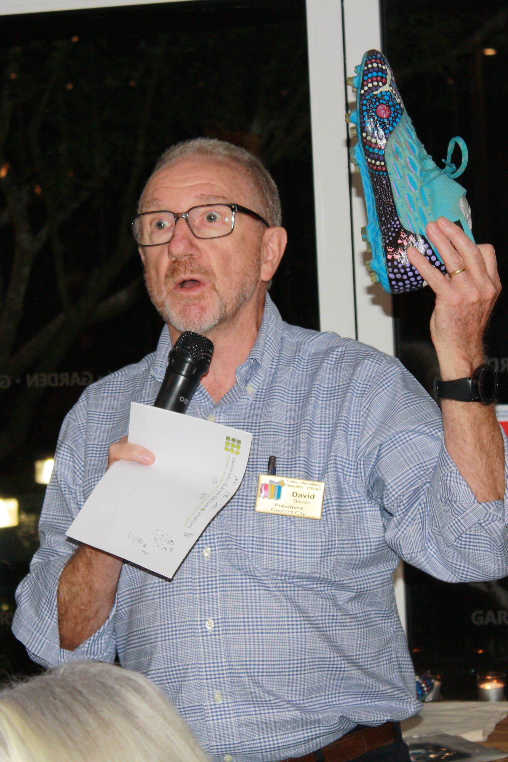 A man is holding a microphone and a piece of paper in his hand.