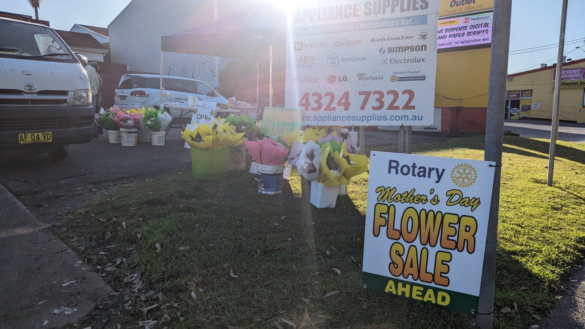 A sign that says ' rotary flower sale ahead ' on it