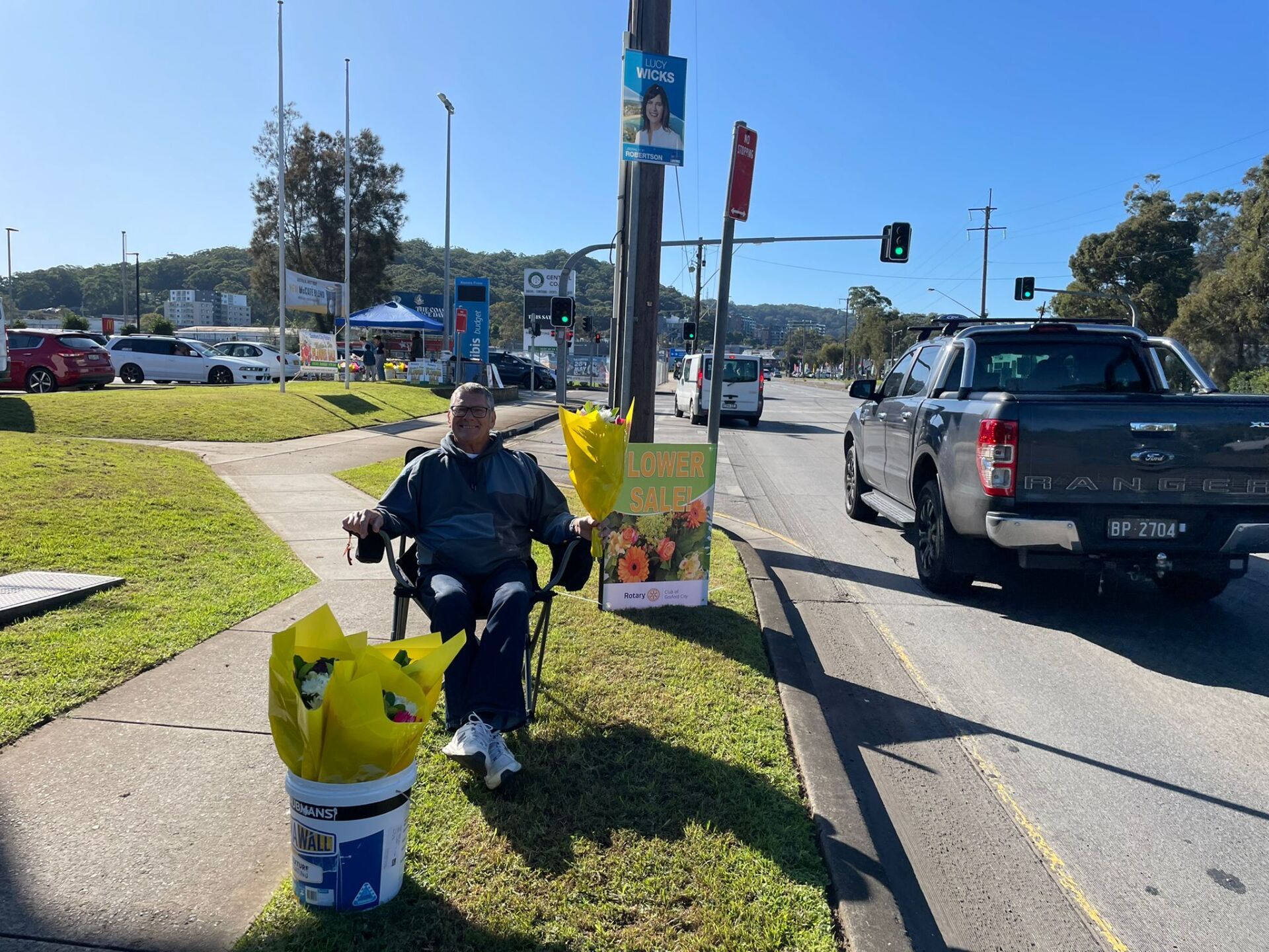 A man is sitting in a chair on the side of the road.