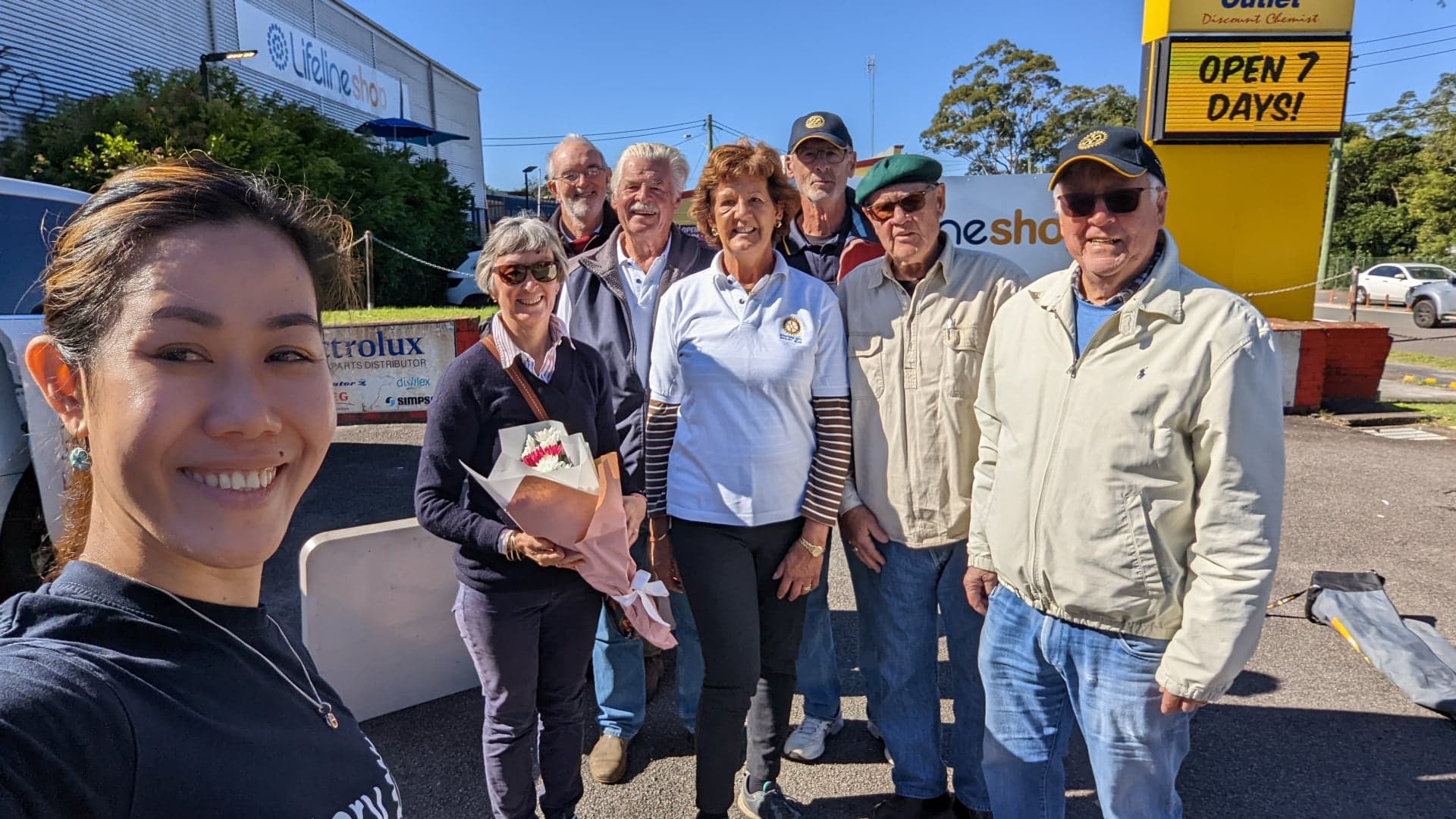 A group of people are standing in front of a yellow sign that says open 2 days.