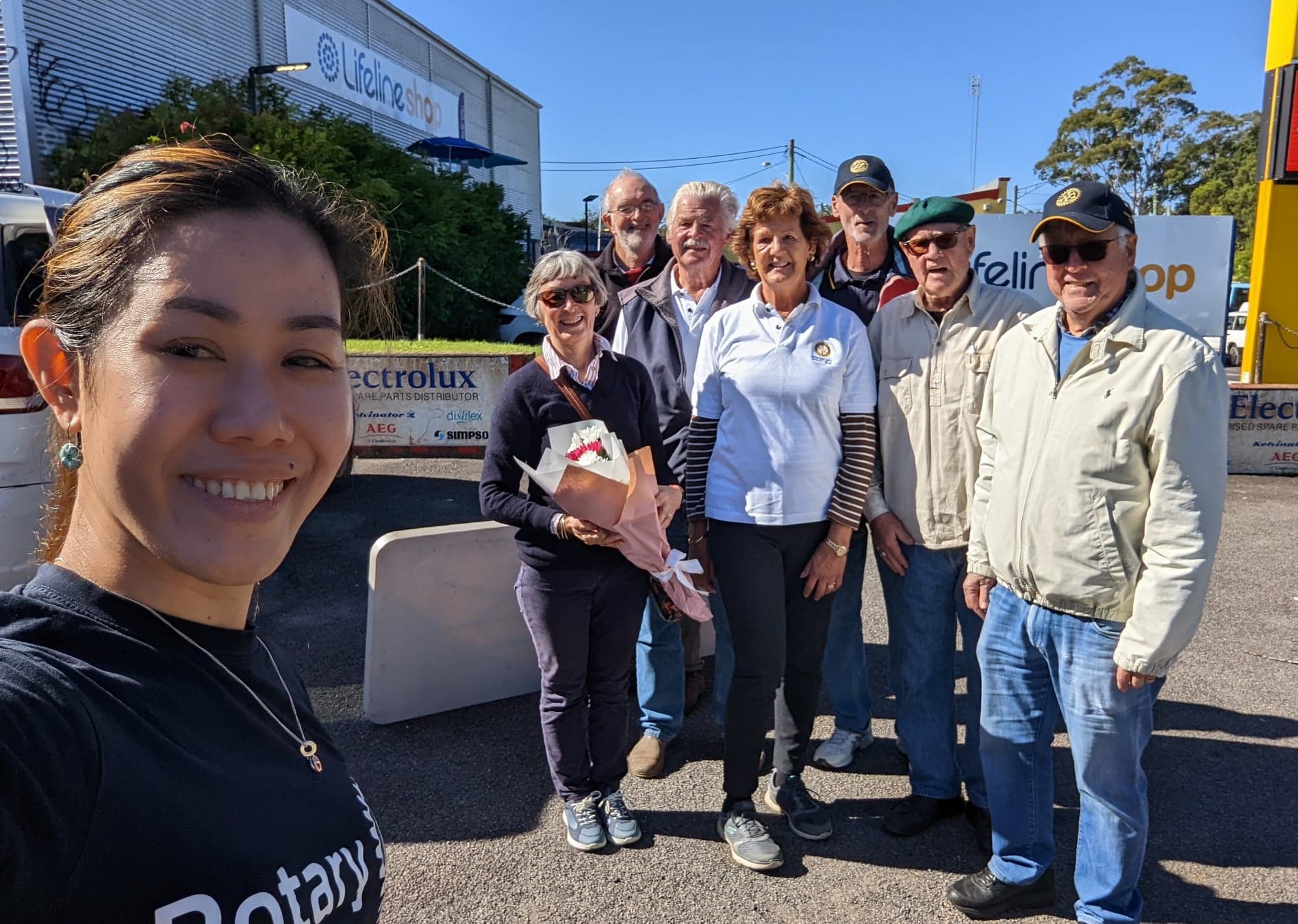 A group of people standing next to each other in a parking lot.