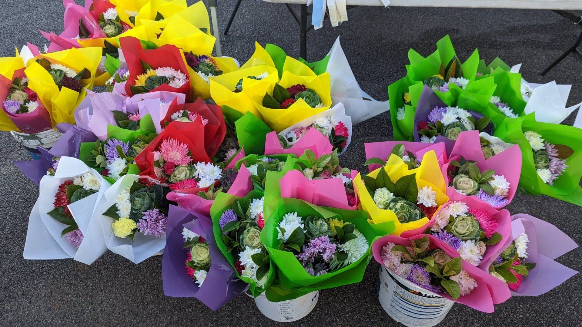 A bunch of different colored flowers are sitting on the ground