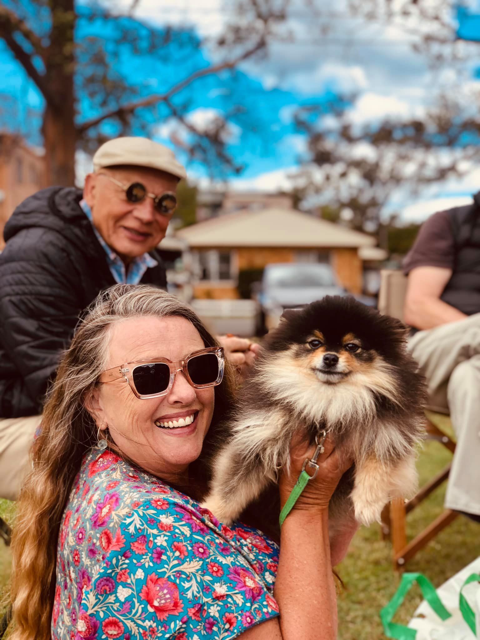 A woman is holding a small dog in her arms.