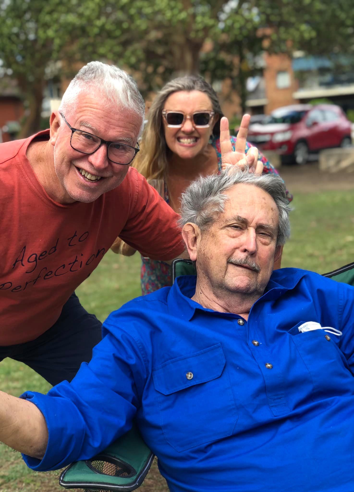 A man in a blue shirt is taking a selfie with two other men and a woman.