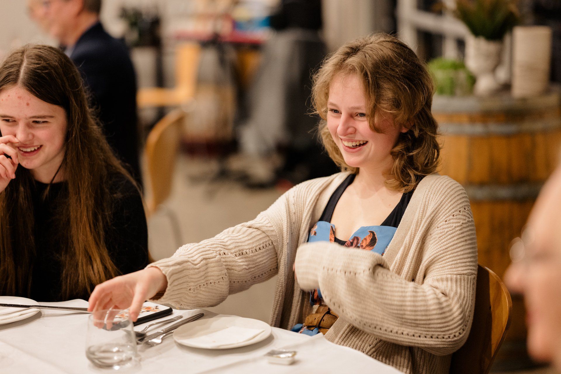 Two young girls are sitting at a table with plates and silverware.