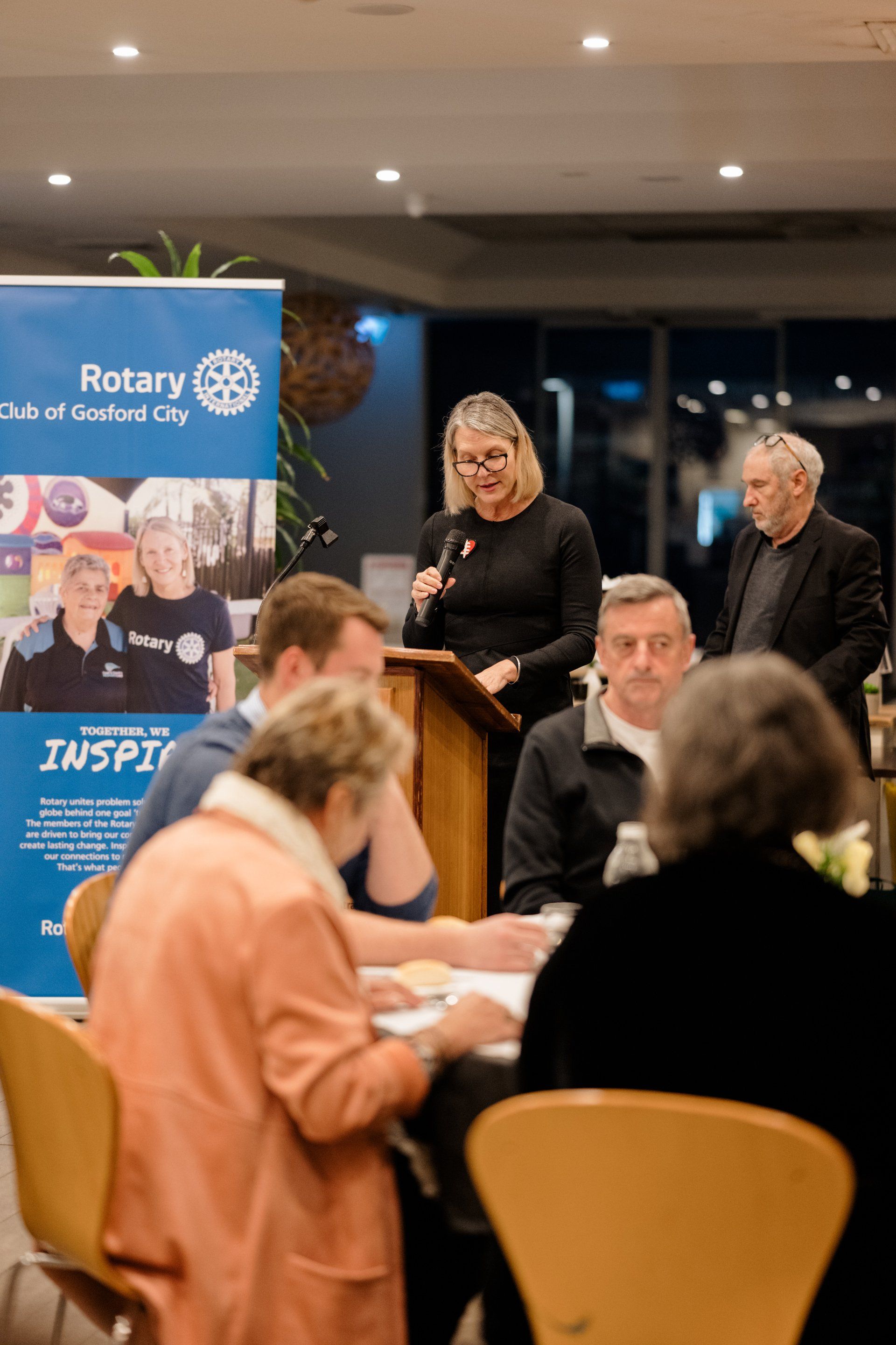 A woman is standing at a podium giving a speech to a group of people.