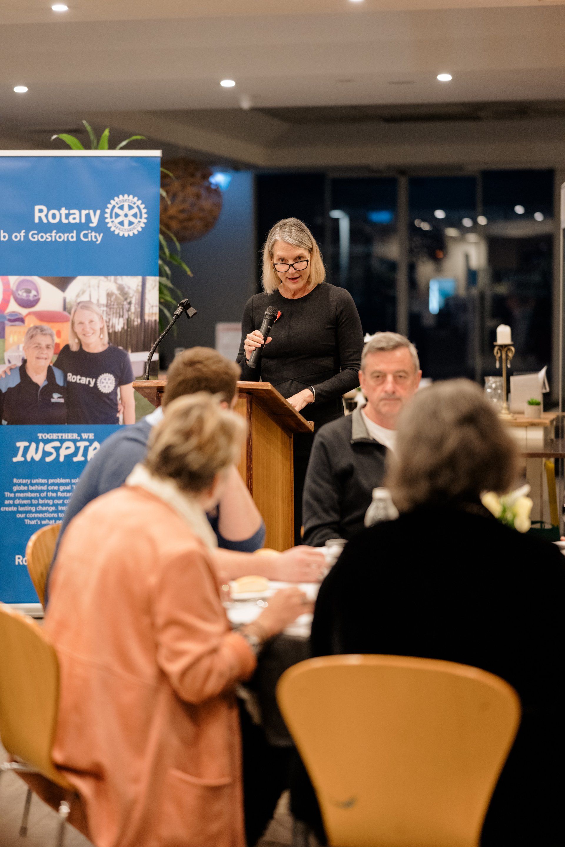 A woman is standing at a podium talking to a group of people.