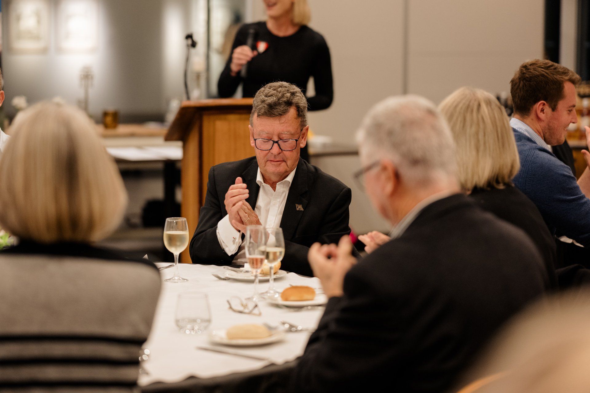 A group of people are sitting at a table with wine glasses.