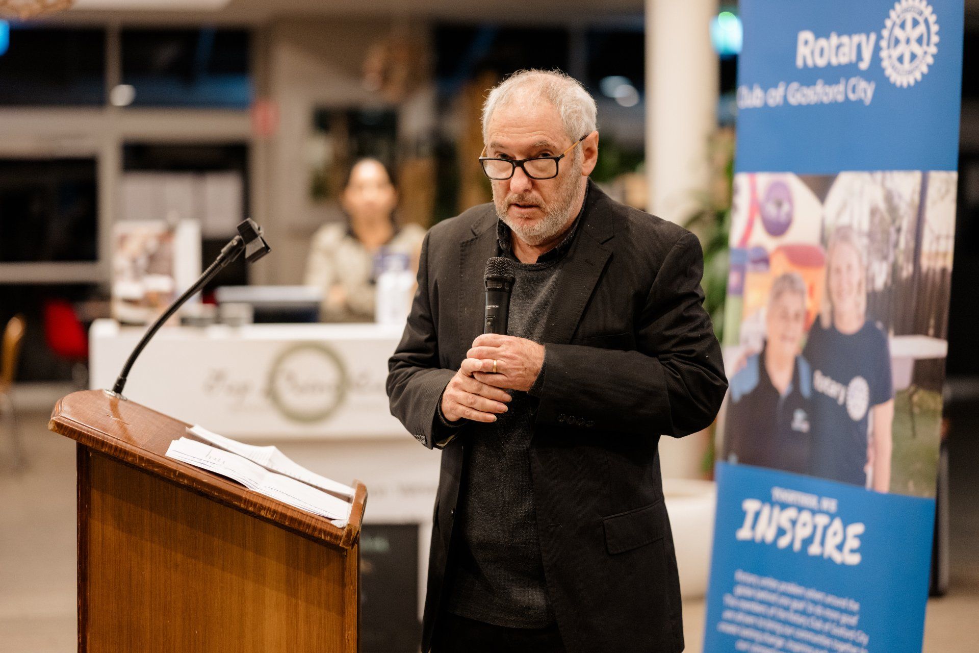 A man is standing at a podium talking into a microphone.