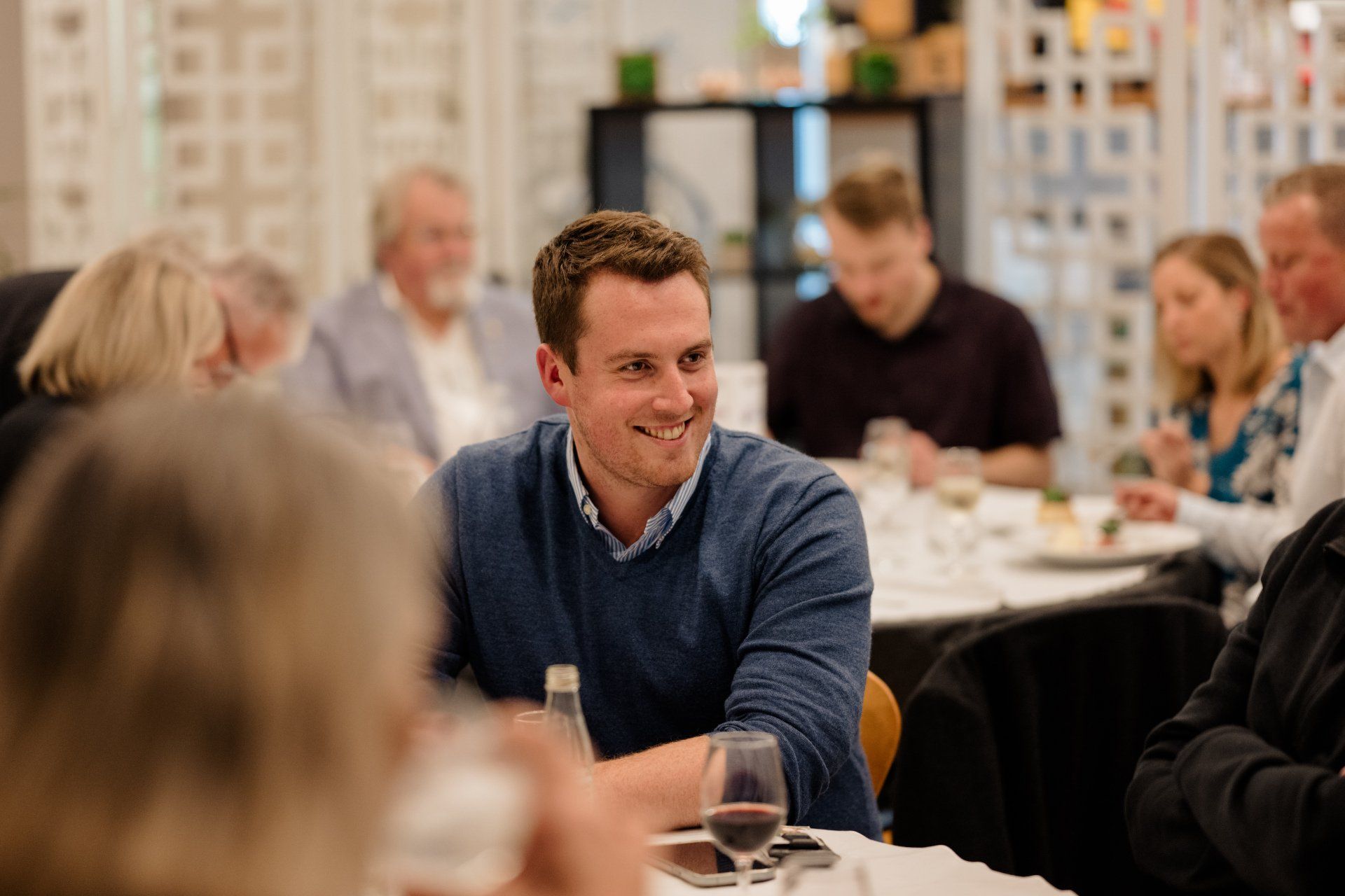 A man is sitting at a table with a glass of wine.