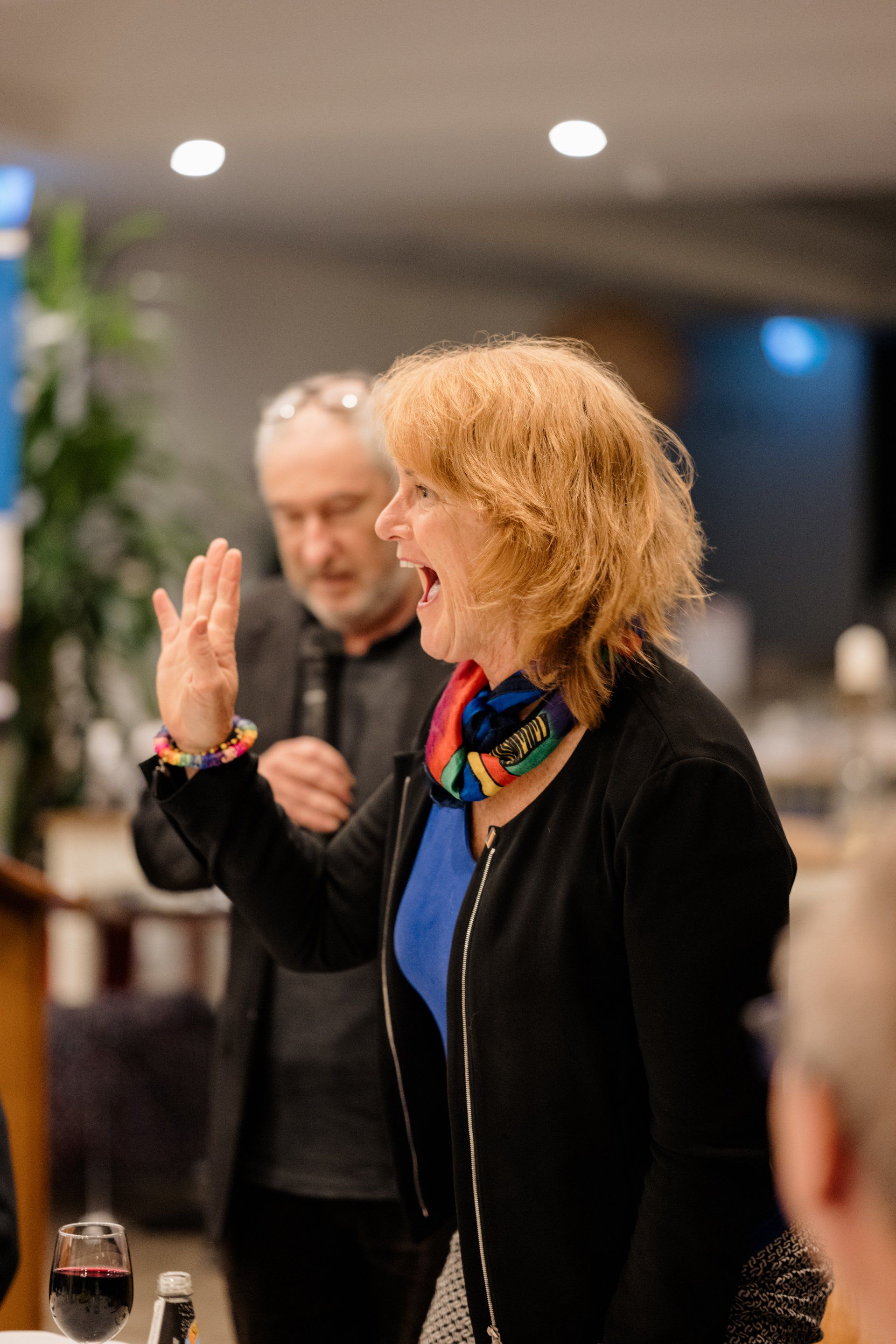 A woman is standing in front of a microphone while a man stands behind her.