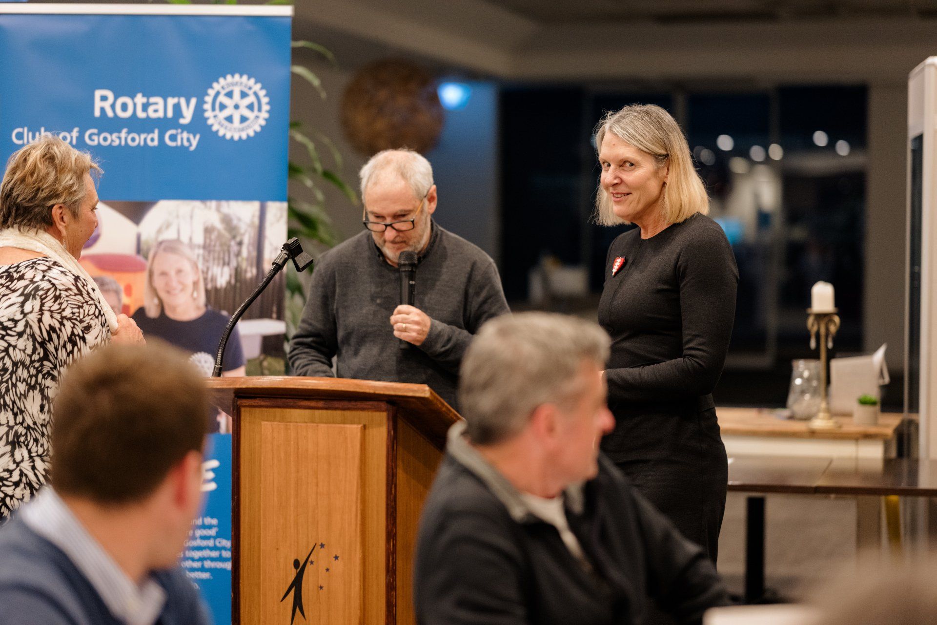 A man and a woman are standing at a podium talking to each other.