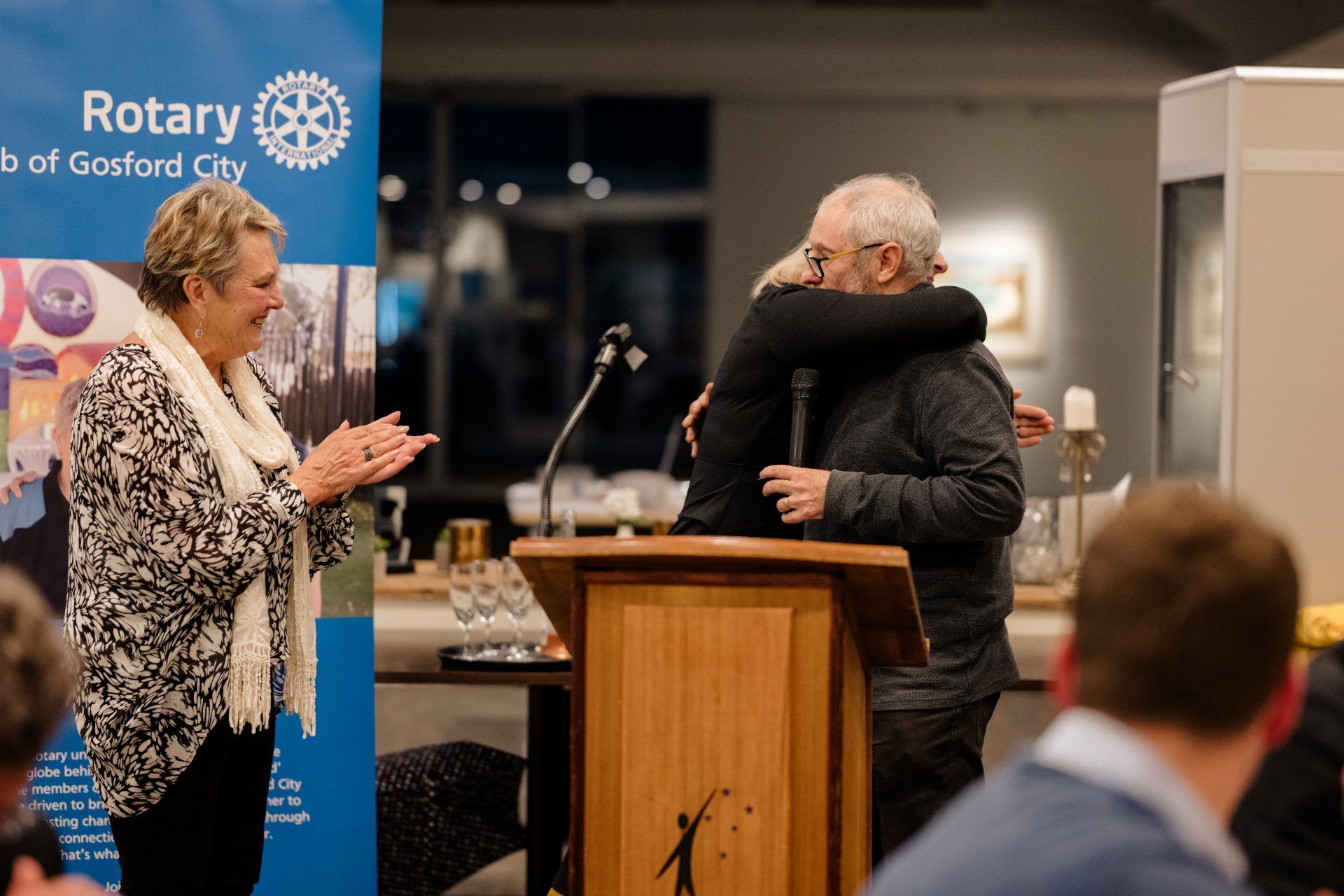 A man and a woman are hugging each other at a podium.