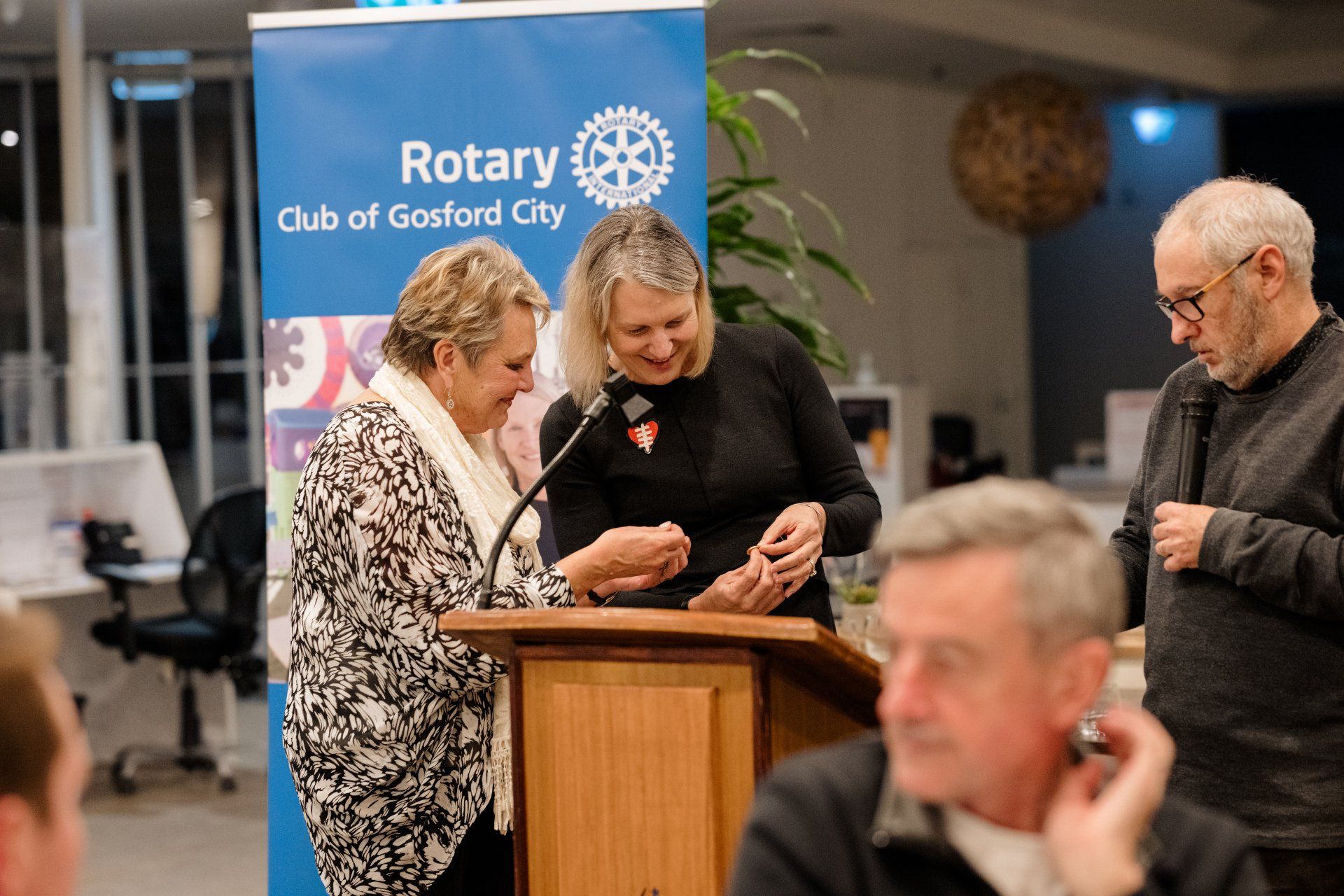 A group of people are standing around a podium talking to each other.