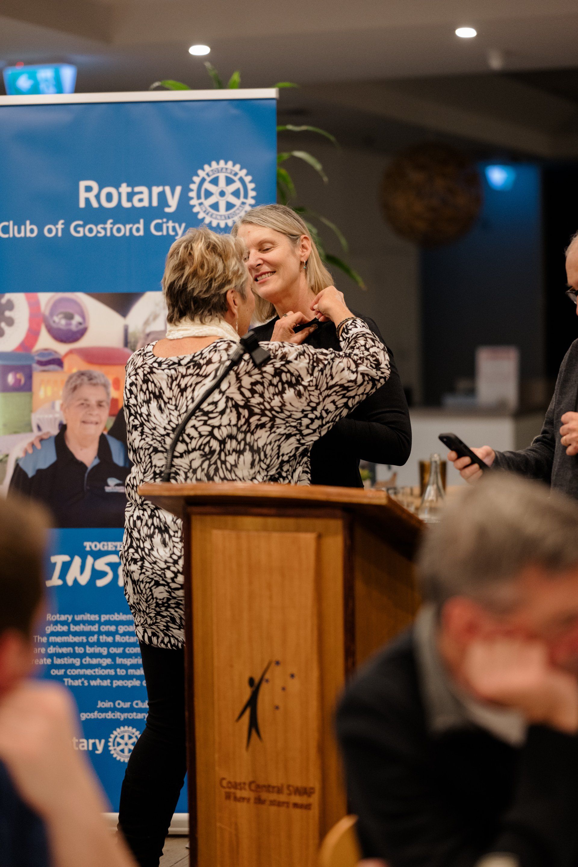 Two women are hugging each other in front of a podium.