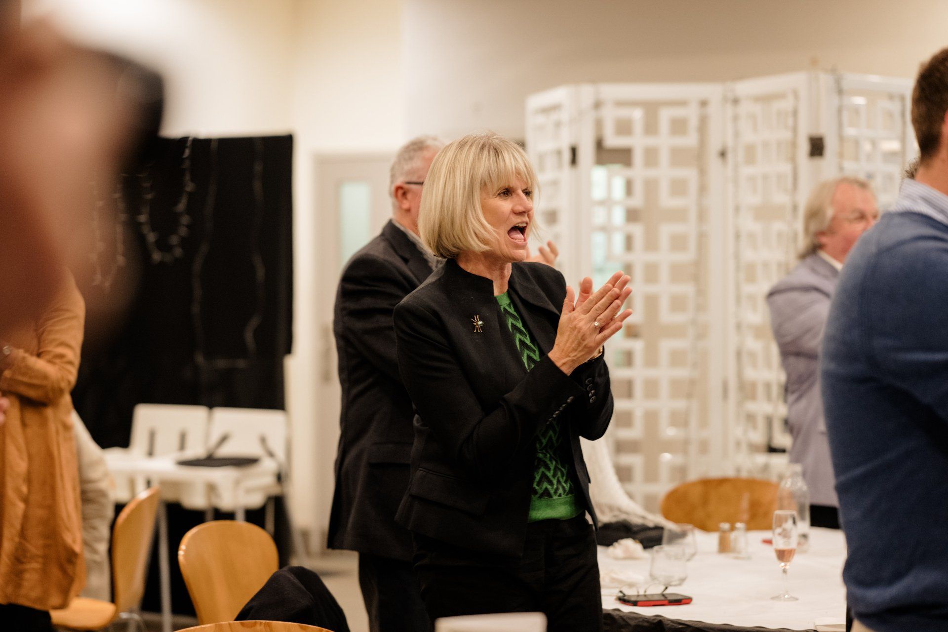 A woman is standing in a room talking to a group of people.
