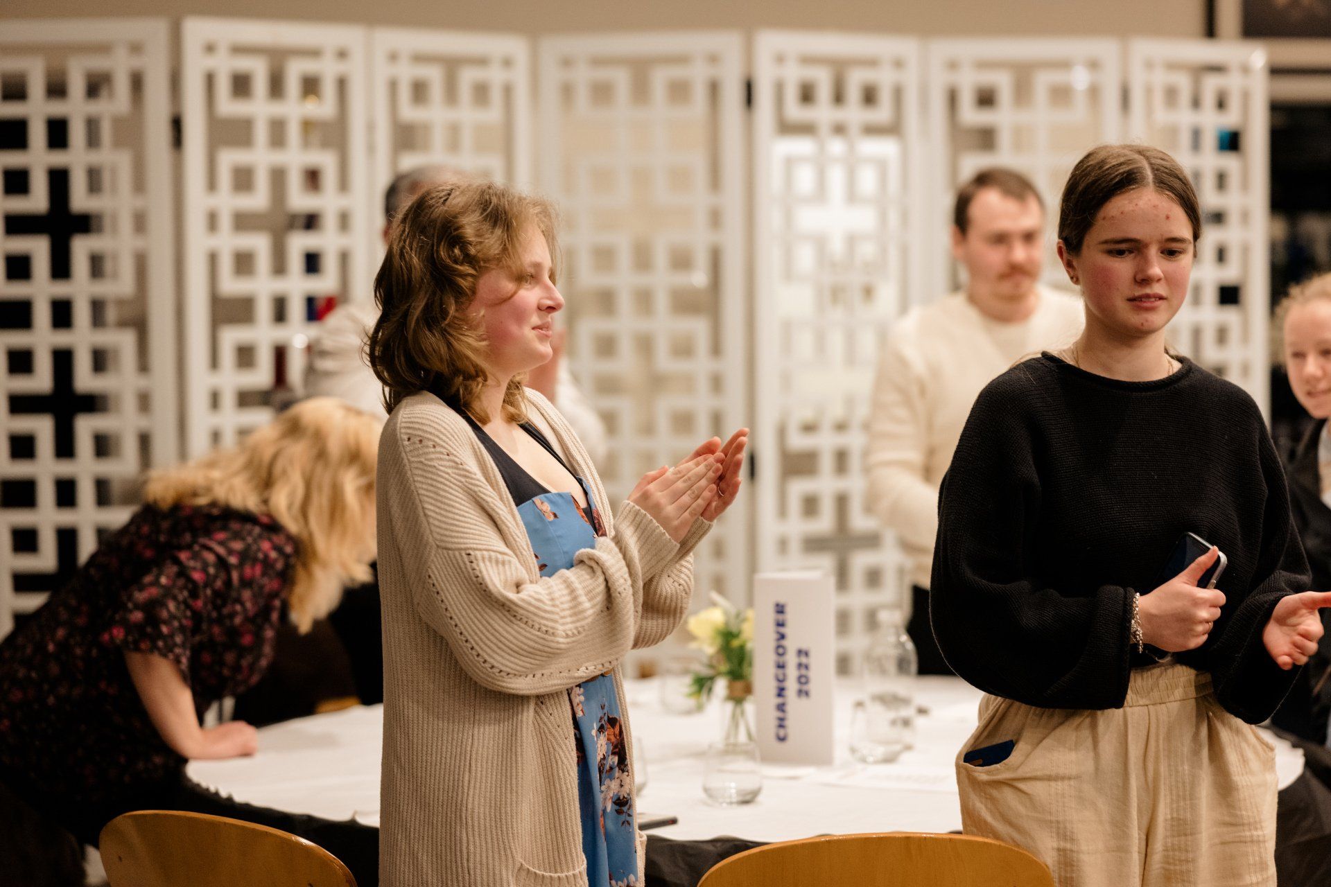 A group of people are standing around a table applauding.