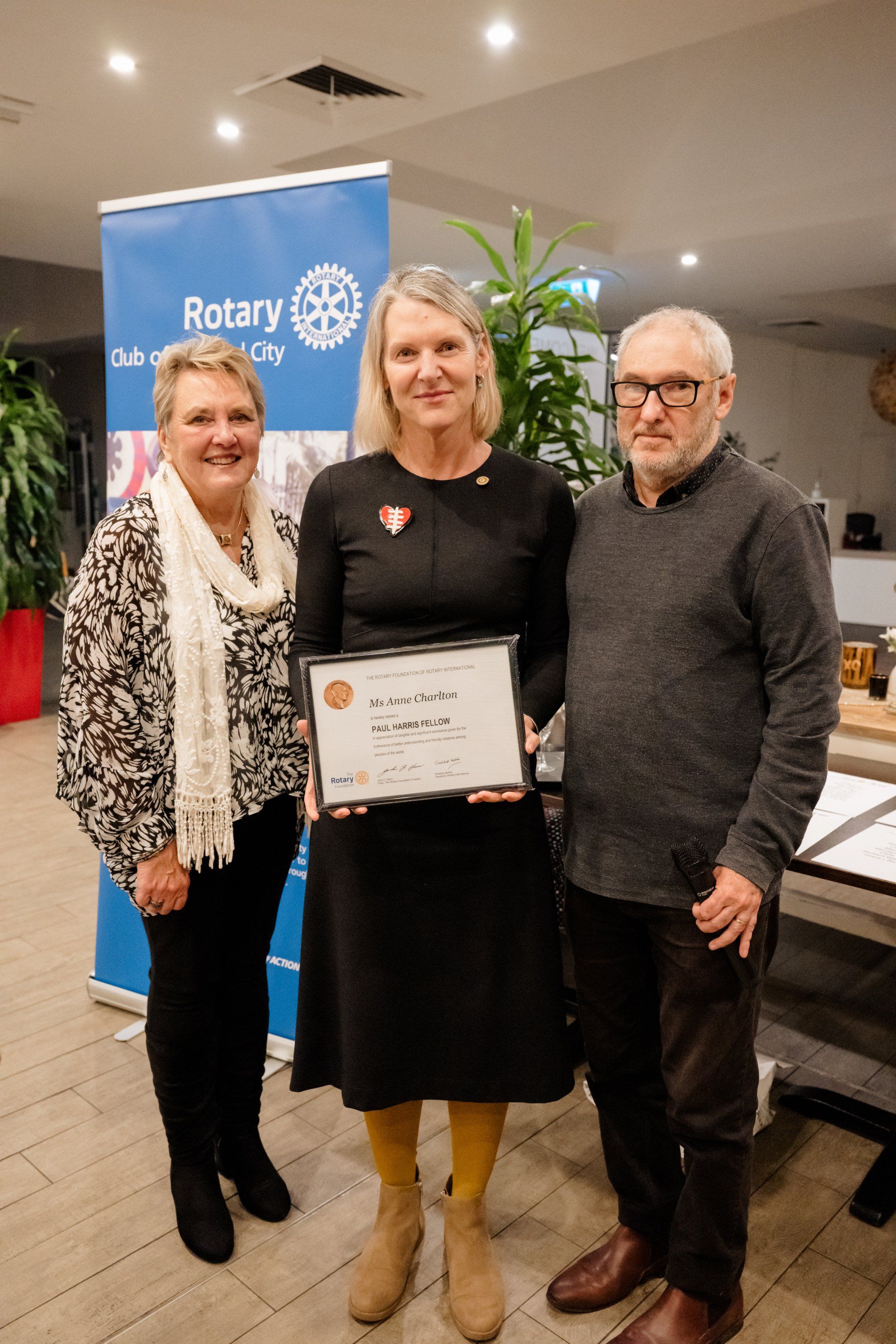 A woman is holding a certificate while standing next to two men.