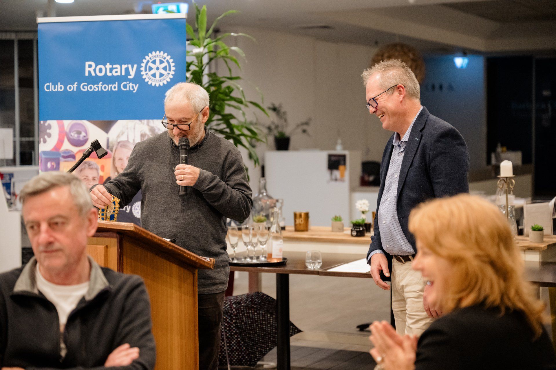A man is giving a speech at a podium in front of a group of people.