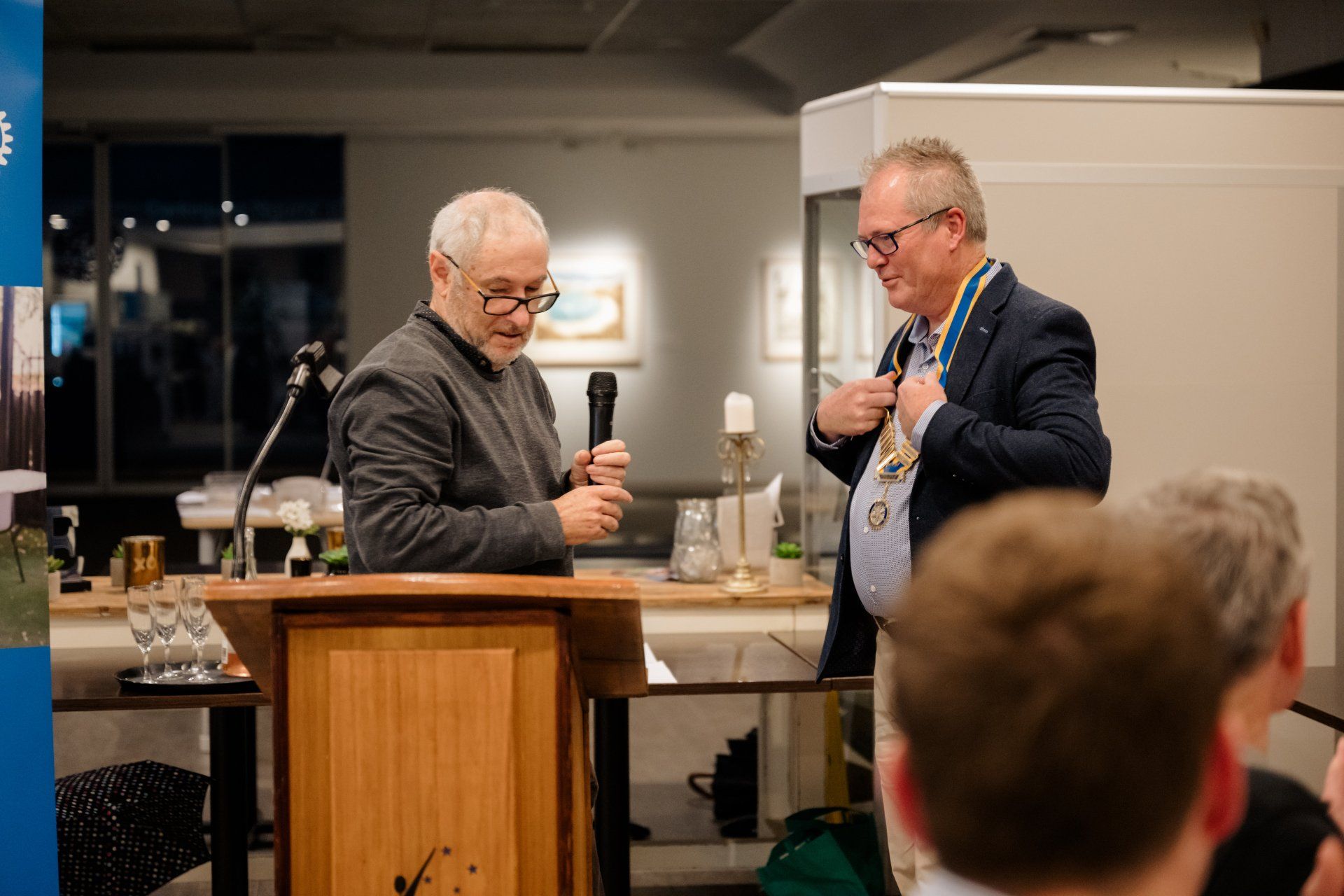 Two men are standing at a podium talking to each other.