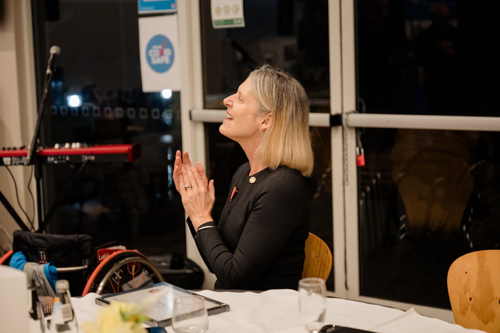 A woman is sitting at a table clapping her hands.