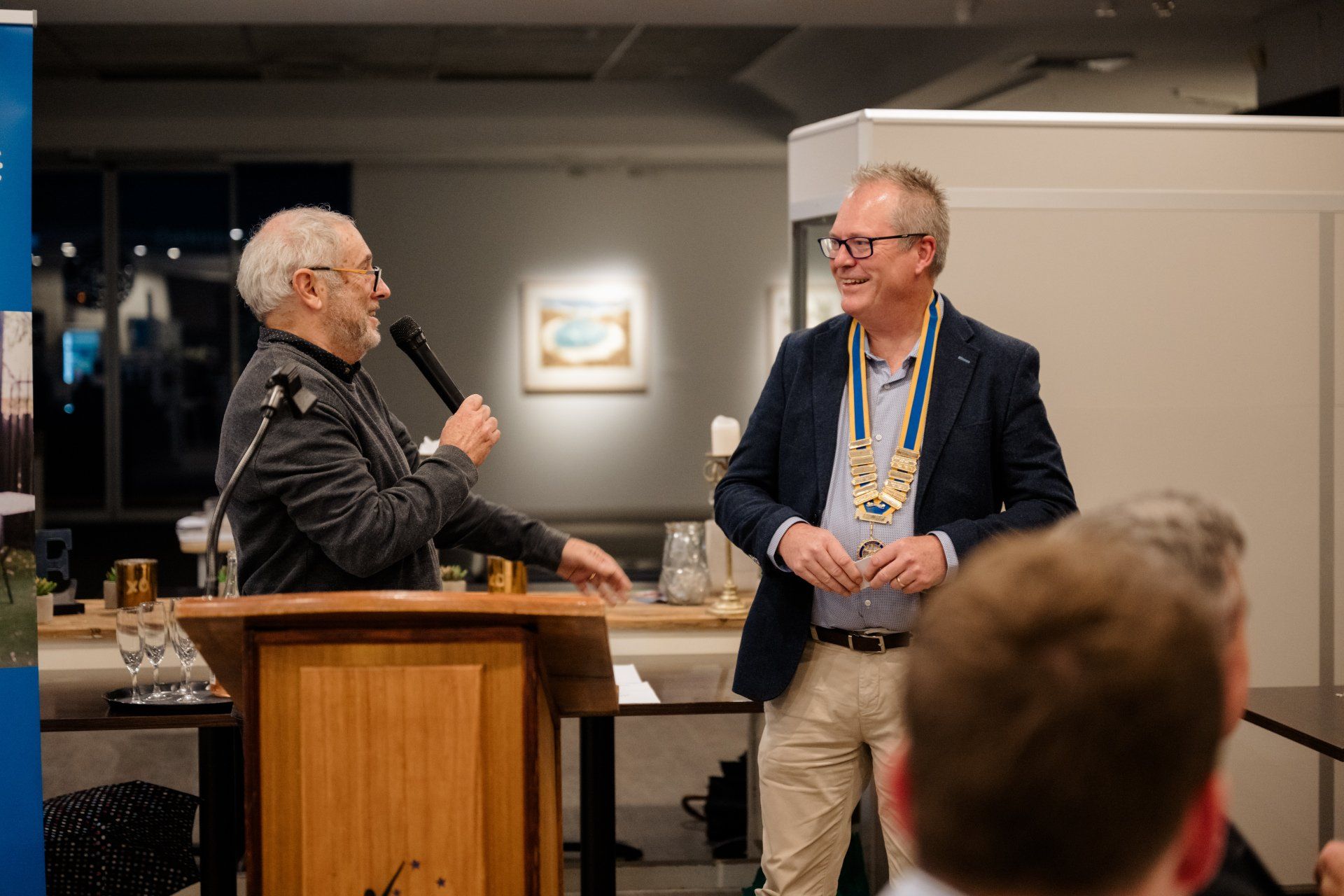 Two men are standing at a podium talking into microphones.