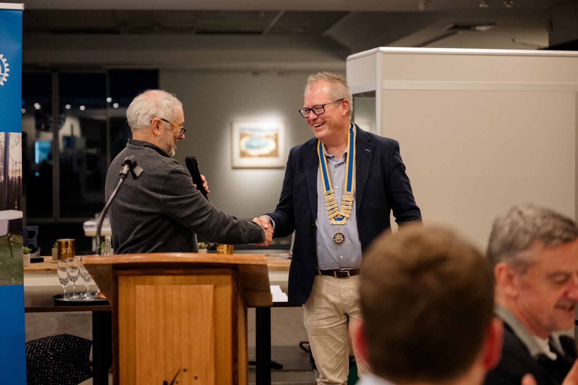 Two men are shaking hands at a podium in front of a microphone.