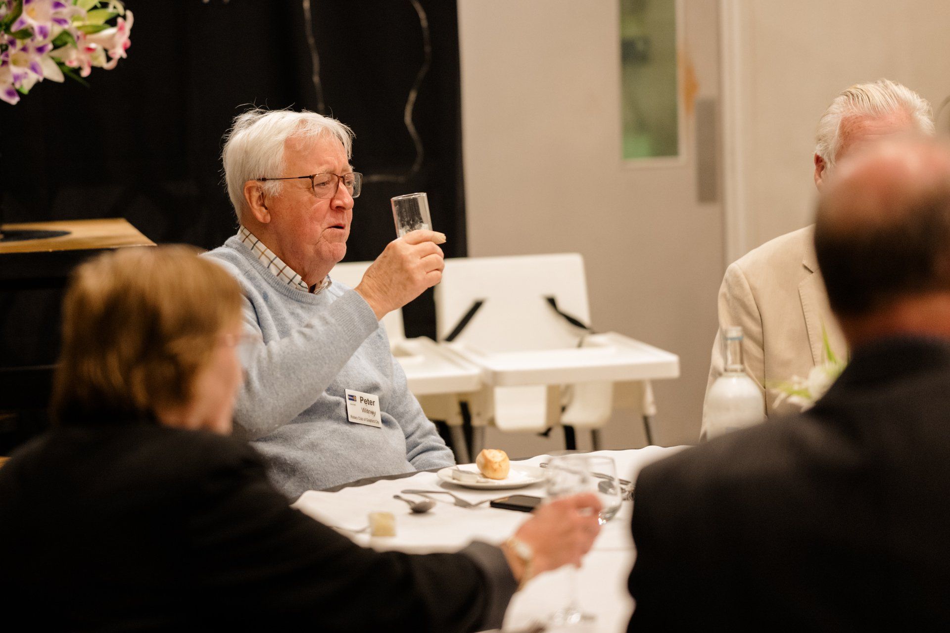 A man is sitting at a table holding a glass of wine.