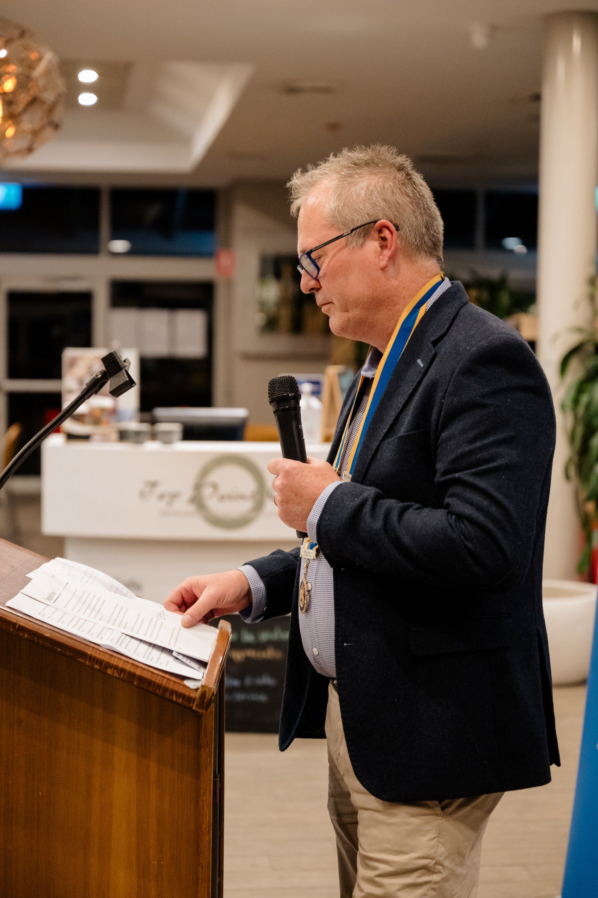 A man in a suit is standing at a podium holding a microphone.