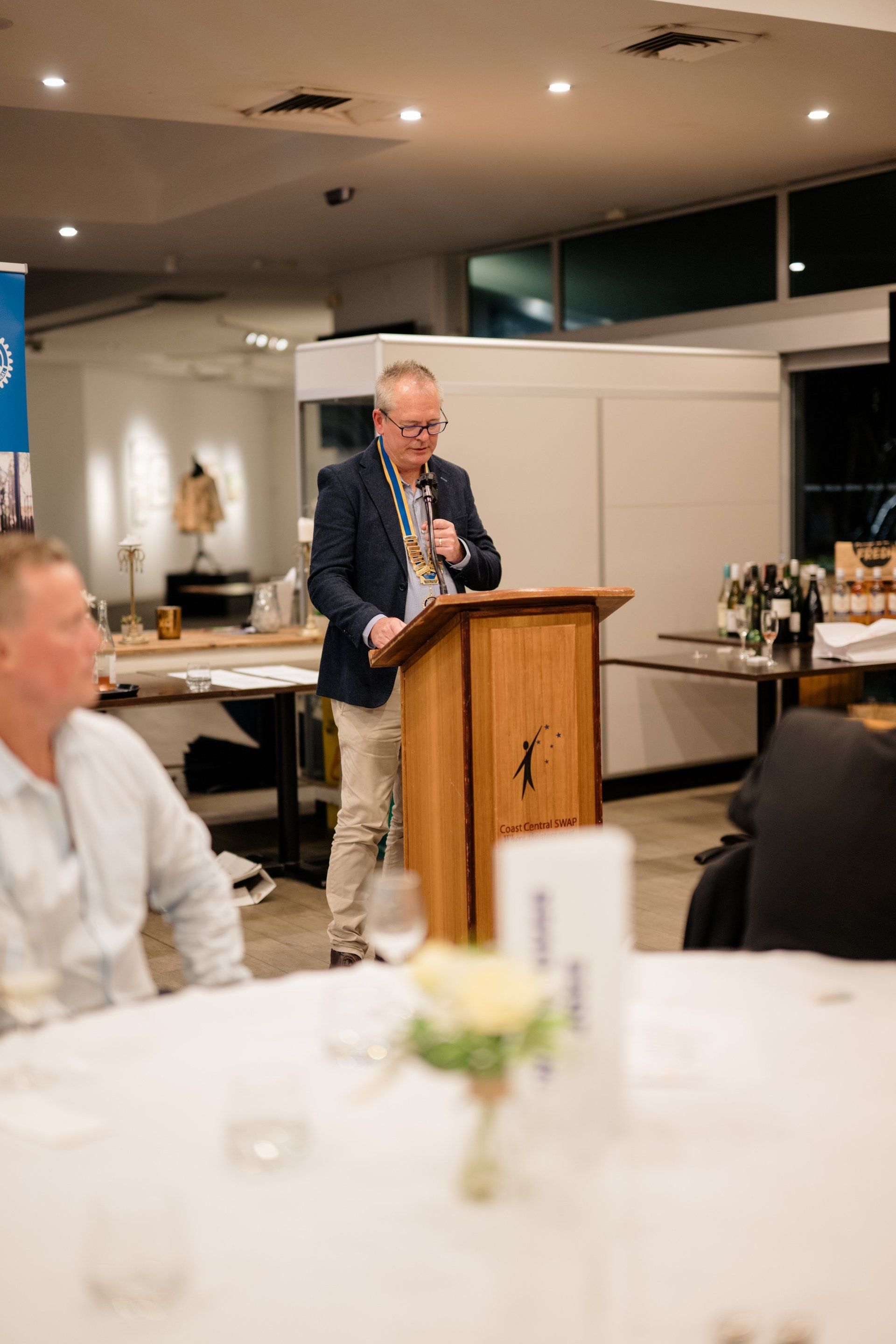A man is standing at a podium giving a speech in a room.