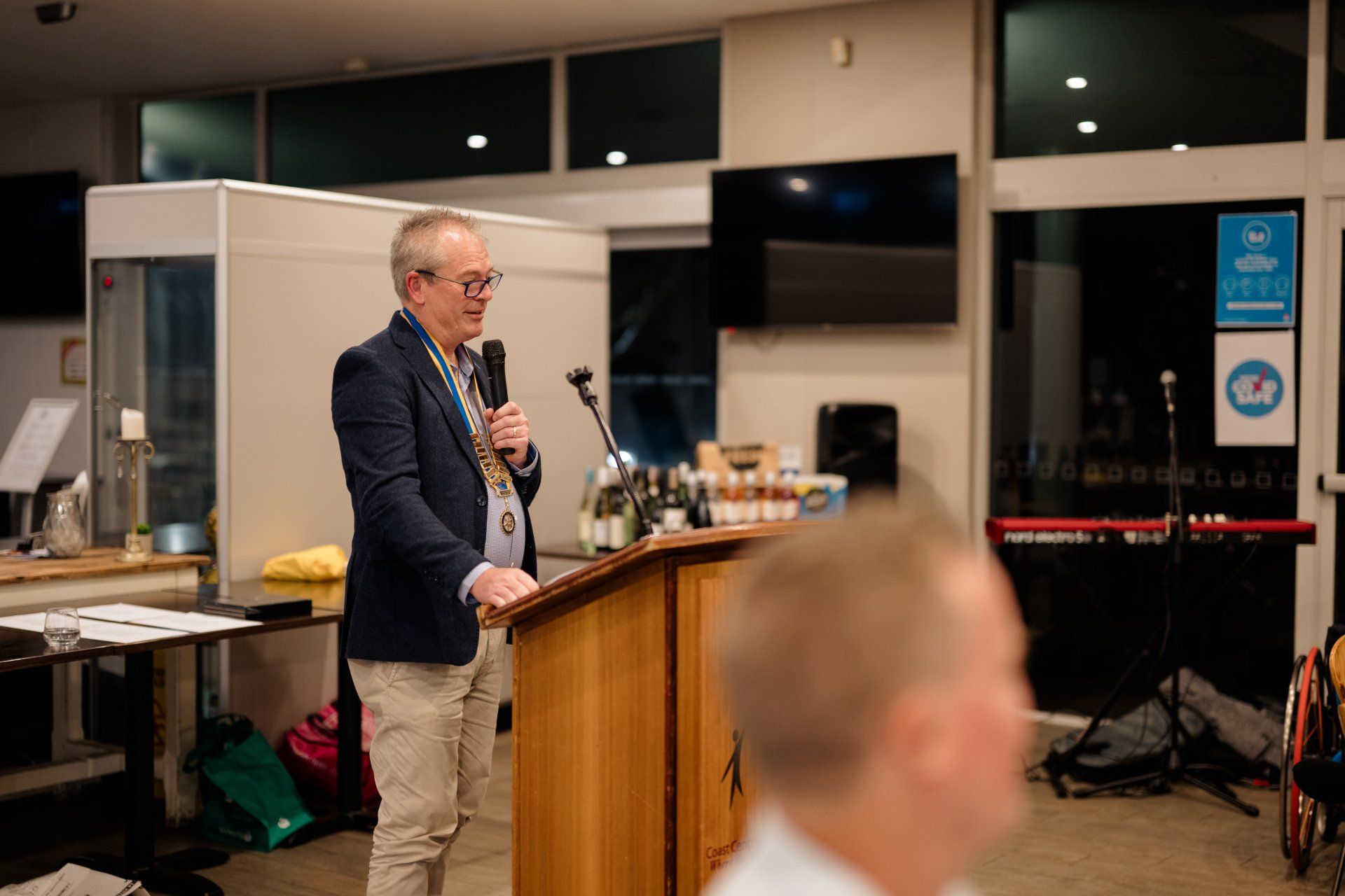 A man is standing at a podium holding a microphone.