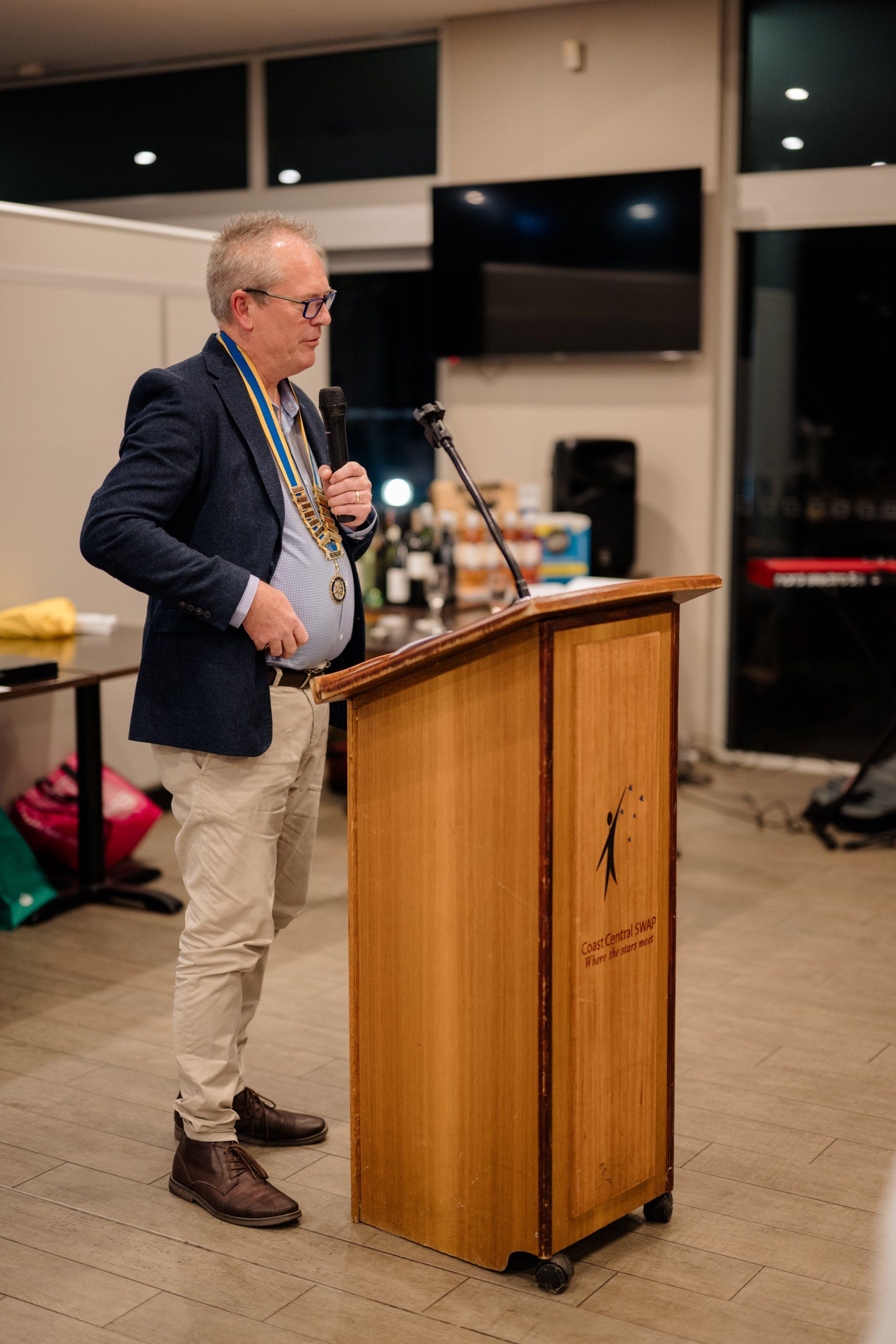 A man is standing at a podium holding a microphone.