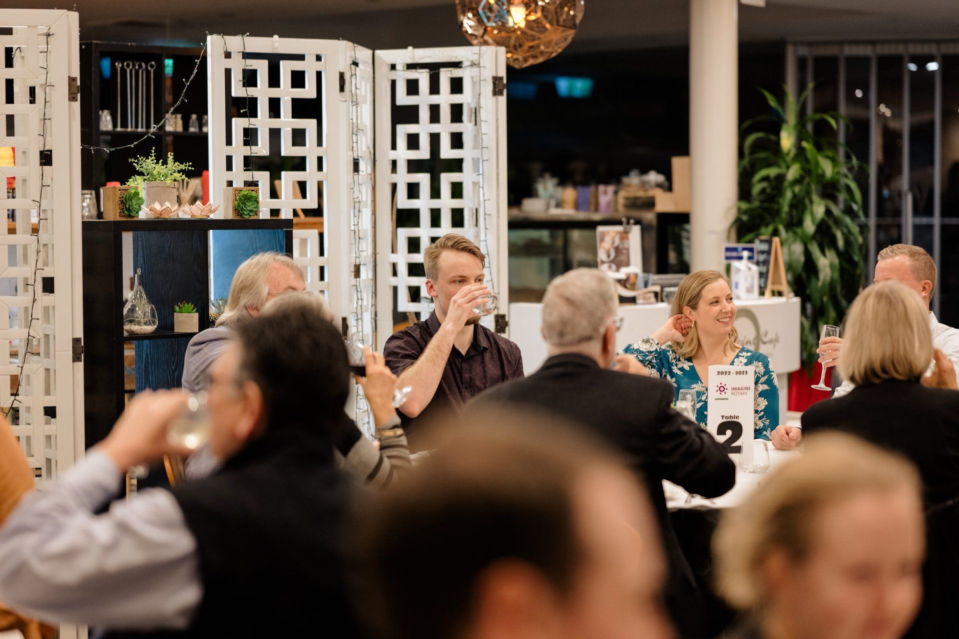 A group of people are sitting at tables in a restaurant drinking wine.